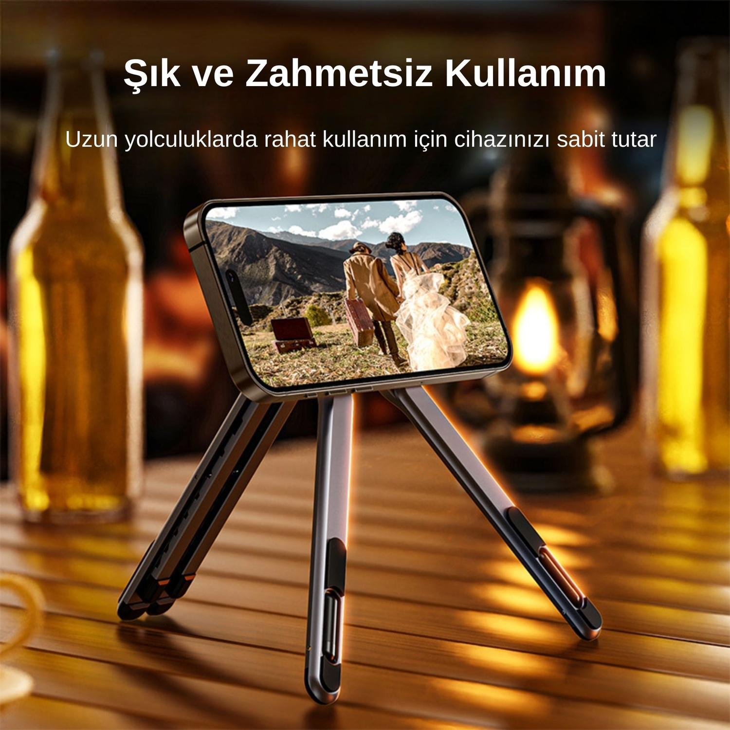 Telefon tripodunda ekranda dağlara karşı iki kişi resmi görünüyor.