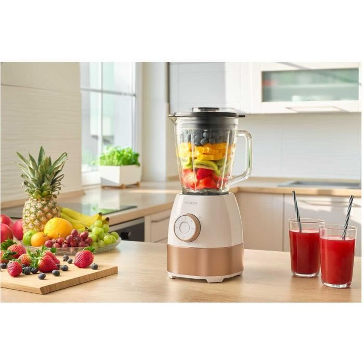 Ein Standmixer mit Obstschichten und zwei Gläsern Saft daneben.