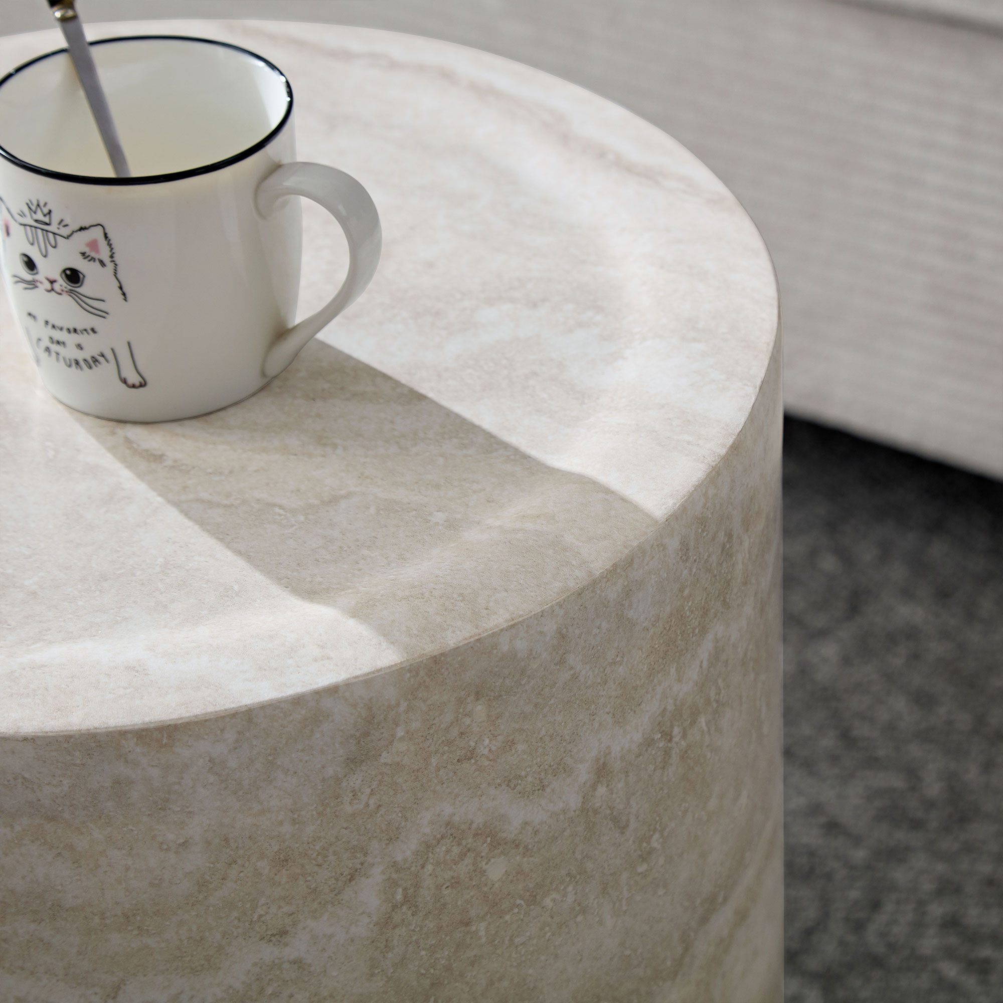 Eine weiße Tasse mit einem Katzenmotiv steht auf einem runden Tisch aus Marmorimitat.
