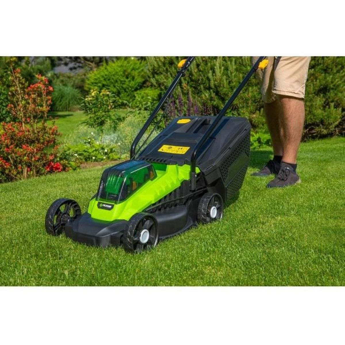 Person mäht einen grünen Rasen mit einem grünen und schwarzen Elektromäher im Garten.