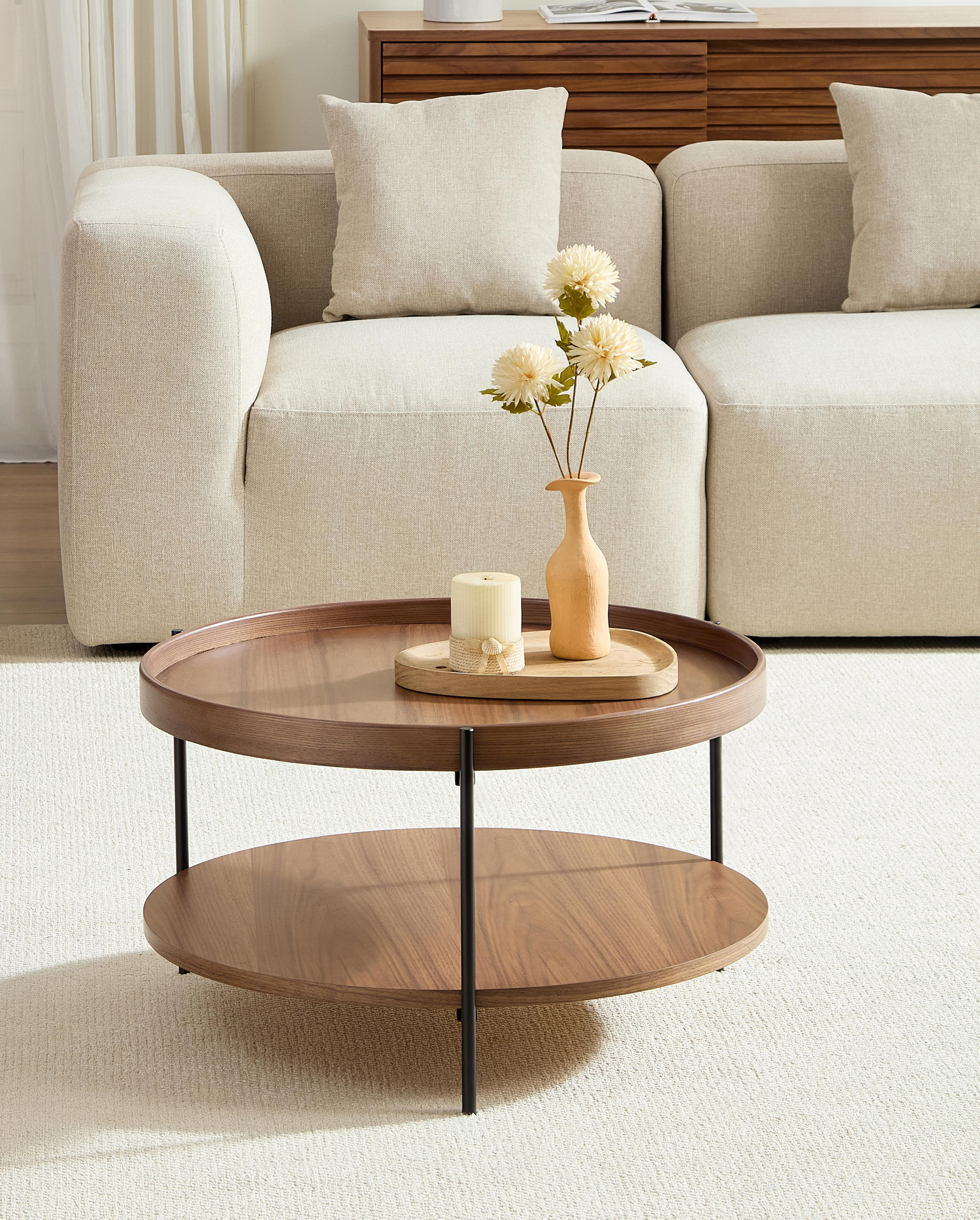 Ein zweistufiger Couchtisch aus Holz mit Kerze und Vase auf einem hellen Teppich.
