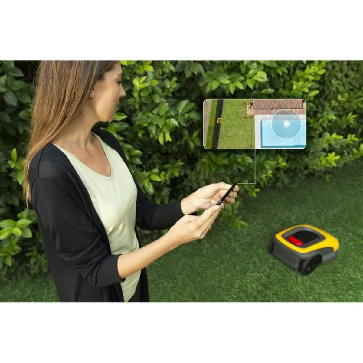 Frau bedient einen Mähroboter mit dem Handy im Garten. Ein Bildschirm zeigt eine Karte.
