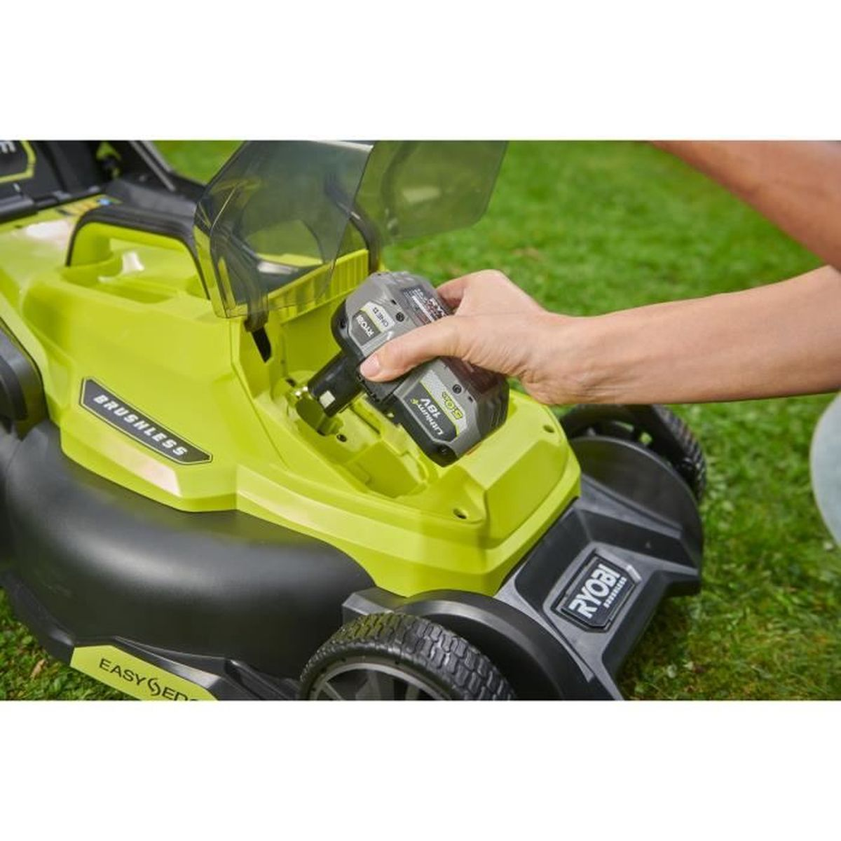 Eine Hand steckt einen Ryobi 18V Akku in einen grün-schwarzen Akku-Rasenmäher.