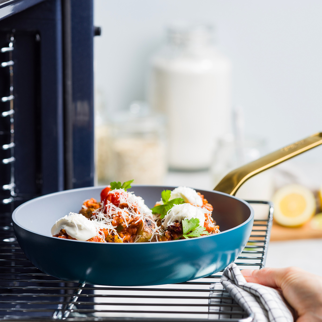 Gefüllte Paprika mit Käse und Kräutern in einer blauen Schüssel auf einem Rost.