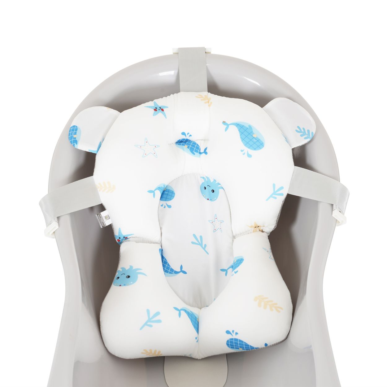 Ein weißes Baby-Badkissen mit Wal- und Seestern-Motiven in einem grauen Babybecken.