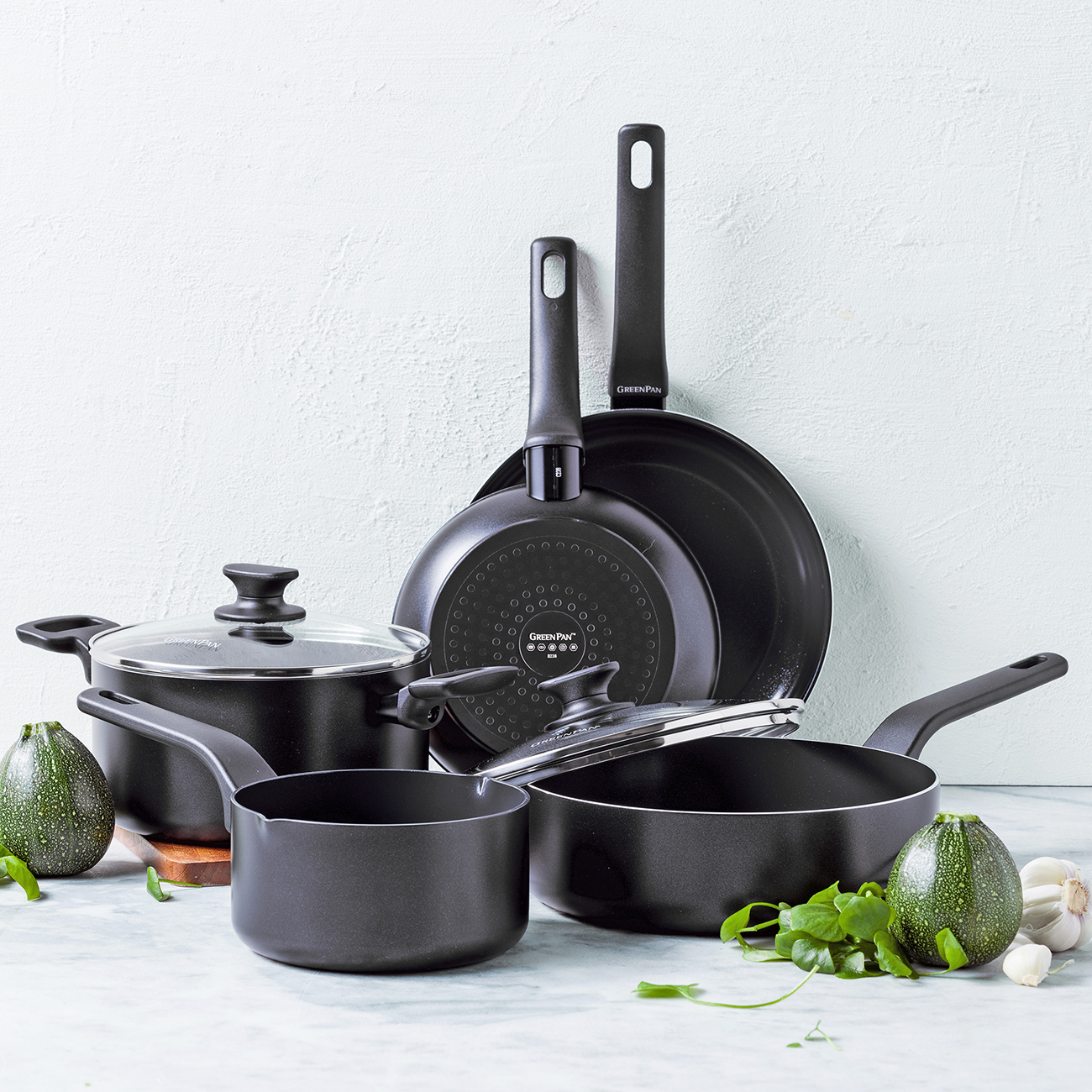 Schwarze Kochgeschirrsammlung mit Zucchini, Knoblauch und Kräutern.
