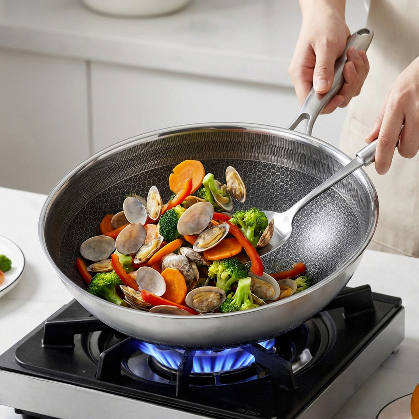 Un wok rempli de palourdes, brocolis, carottes et poivrons rouges est cuit sur une cuisinière à gaz.