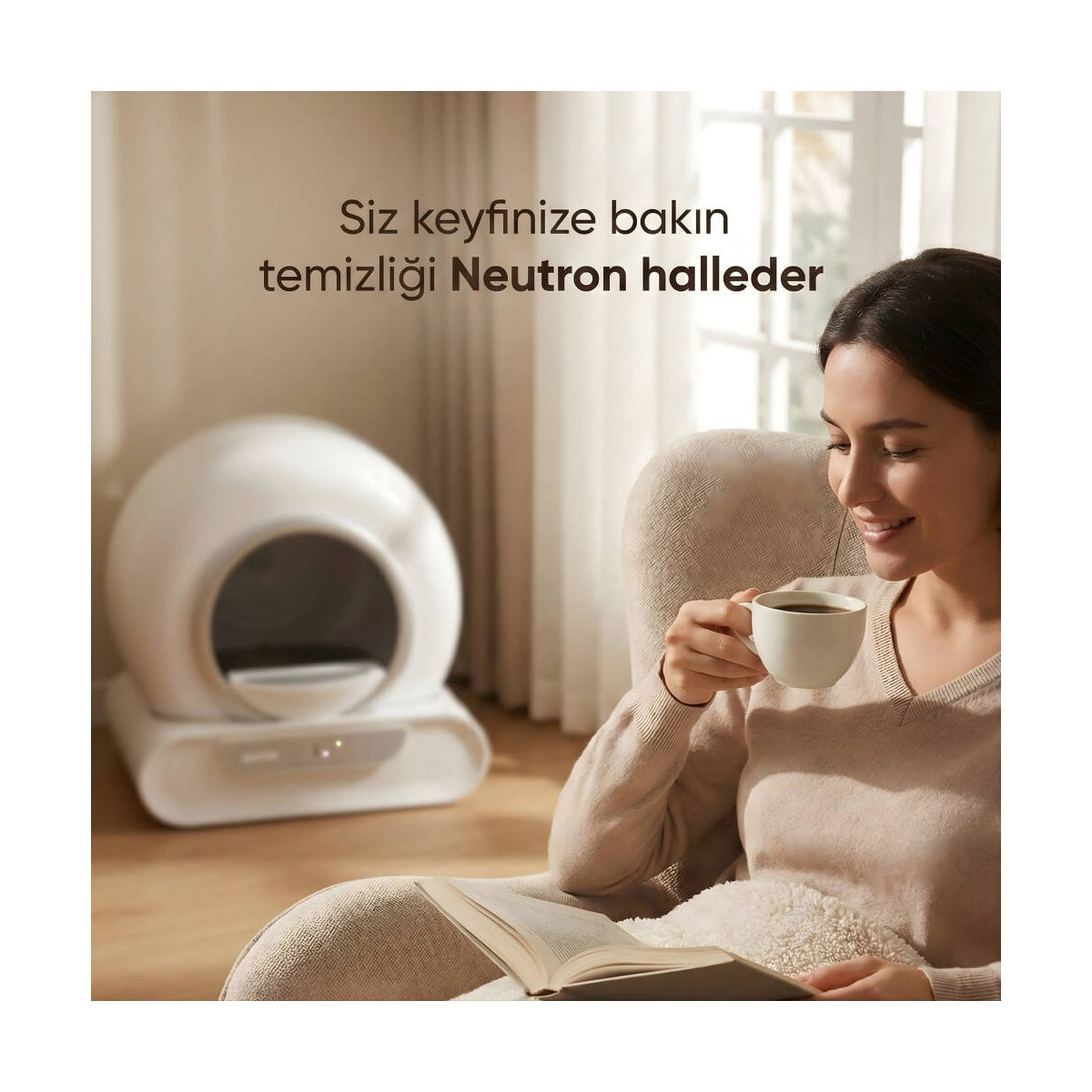 Kadın koltukta oturmuş kitap okuyor, yanında kedi tuvaletiyle kahve içiyor.