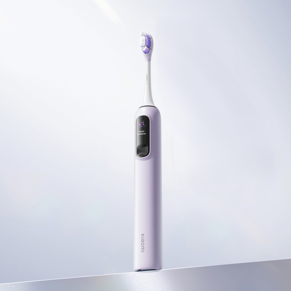 Jasnofioletowa szczoteczka elektryczna z małym ekranem i fioletowym włosiem.
