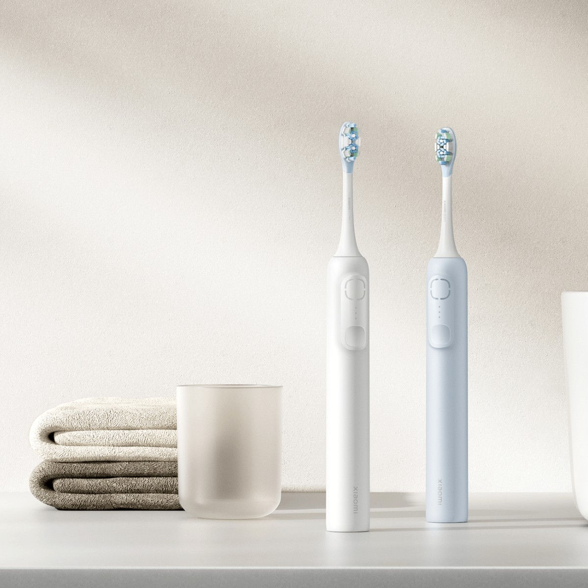 Dwie szczoteczki elektryczne, biała i niebieska, stoją obok siebie.