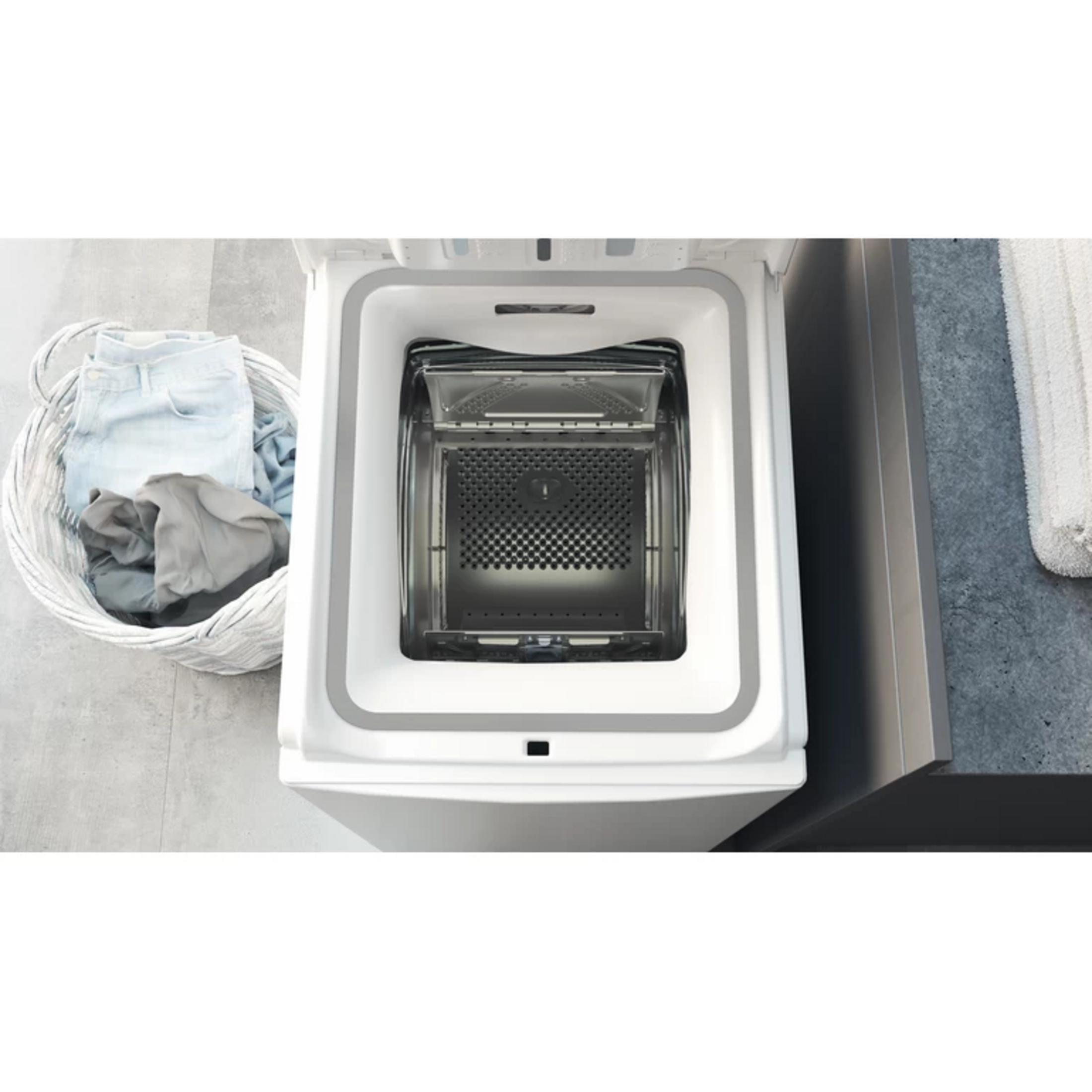 Weiße Waschmaschine mit offenem Deckel, daneben ein Wäschekorb mit Kleidung.