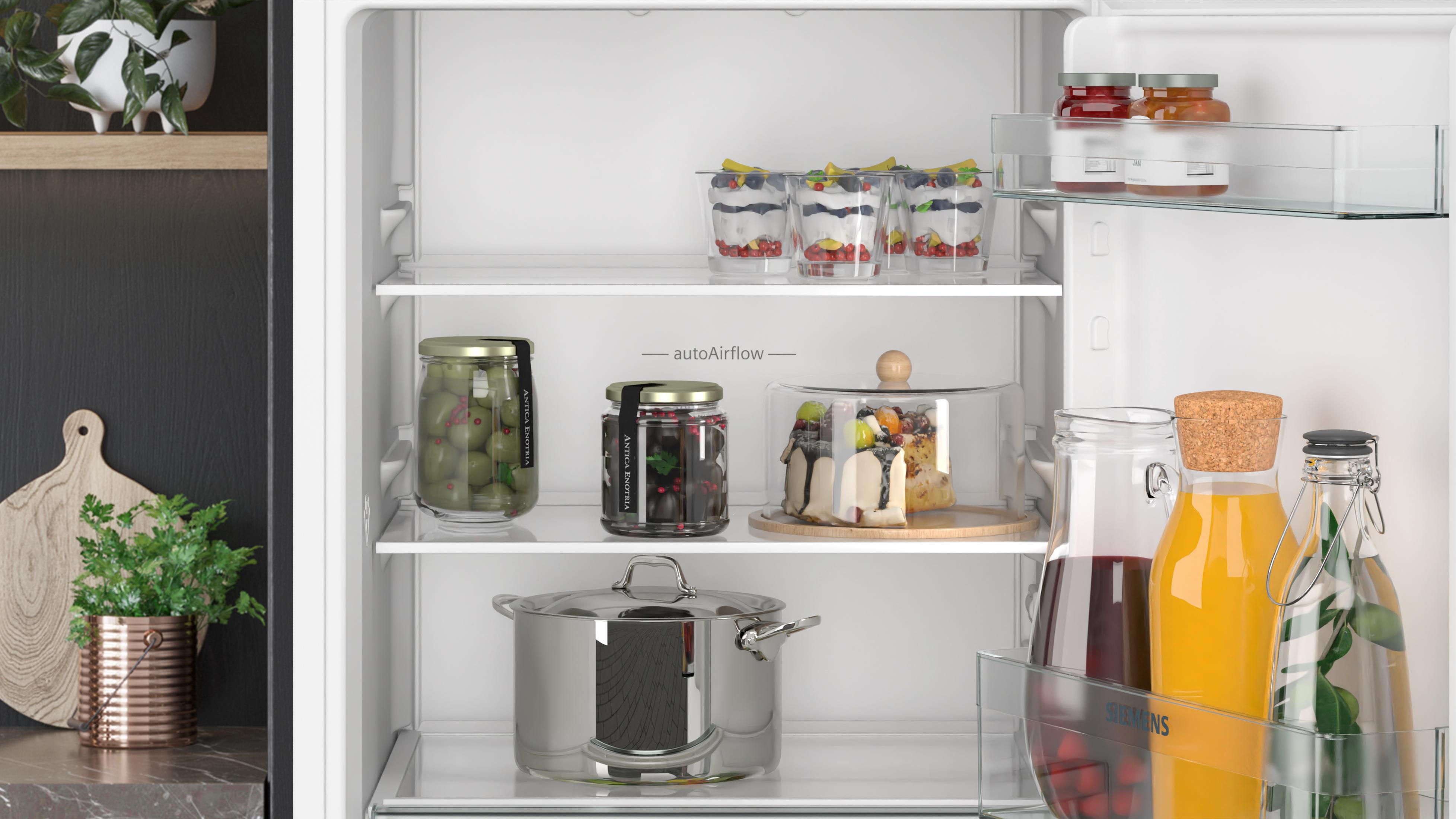 Gefüllte Gläser, Oliven, eine Pfanne, Kuchen und Getränke in einem Kühlschrank.