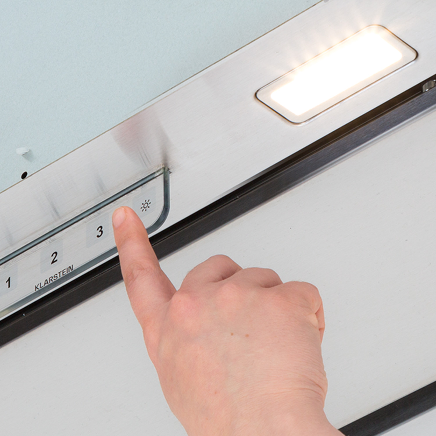 Una mano preme un pulsante su un pannello di controllo illuminato.
