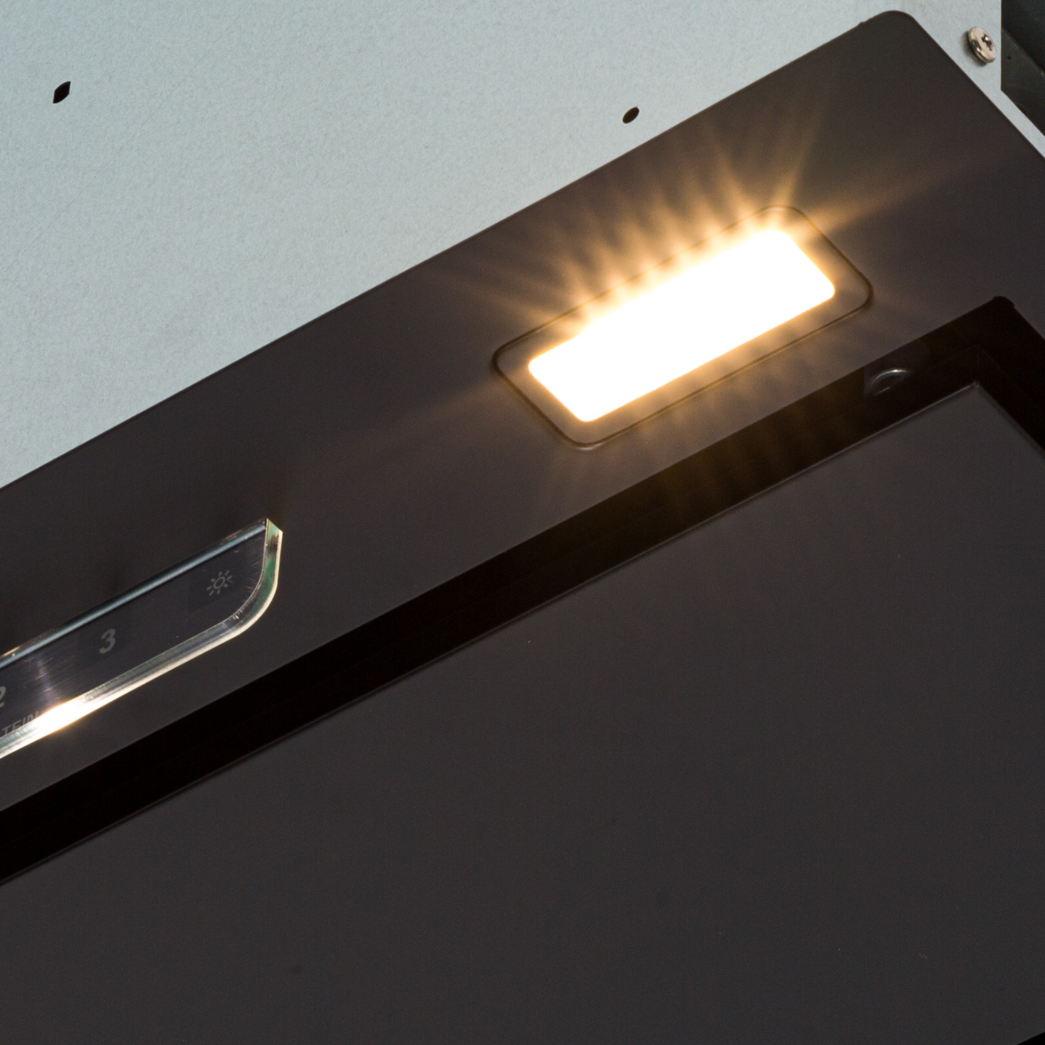 Una luce brillante brilla da un'apertura rettangolare su una cappa aspirante nera.