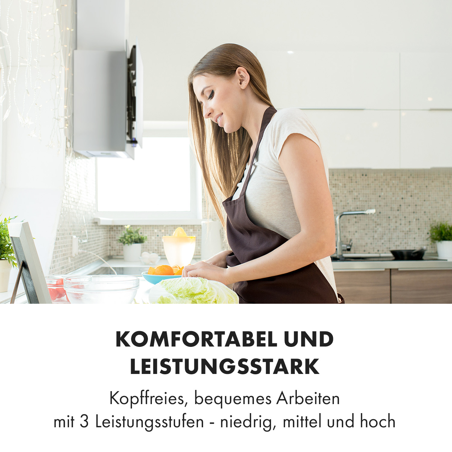 Frau in brauner Schürze kocht in heller Küche mit Obst und Gemüse.