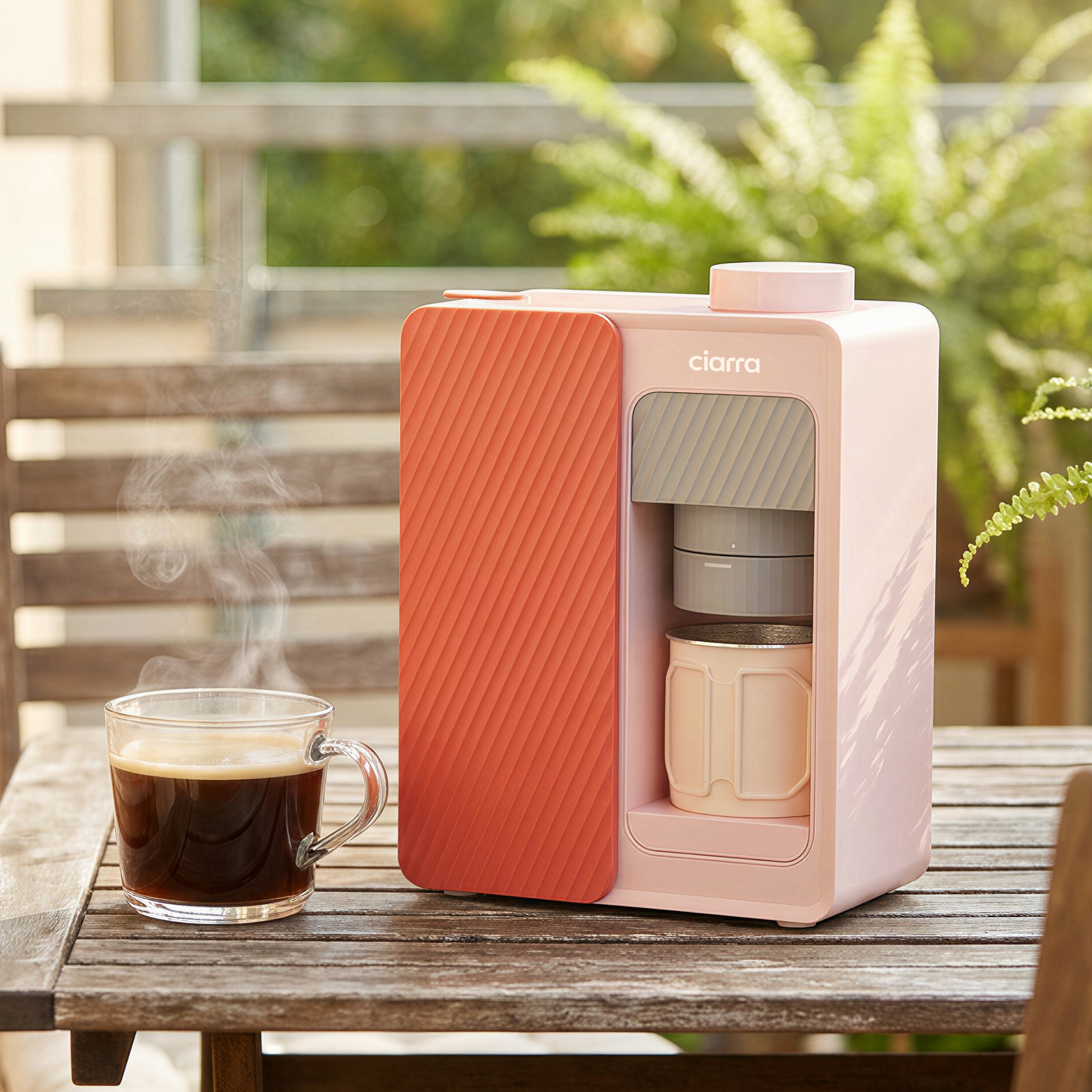 Eine rosa Kaffeemaschine mit einer orangen Vorderseite steht auf einem Holztisch.