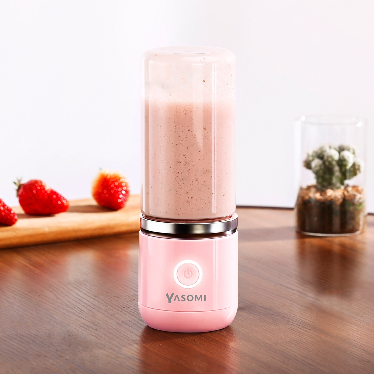 Arka planda çilek ve kaktüs bulunan pembe bir blender.