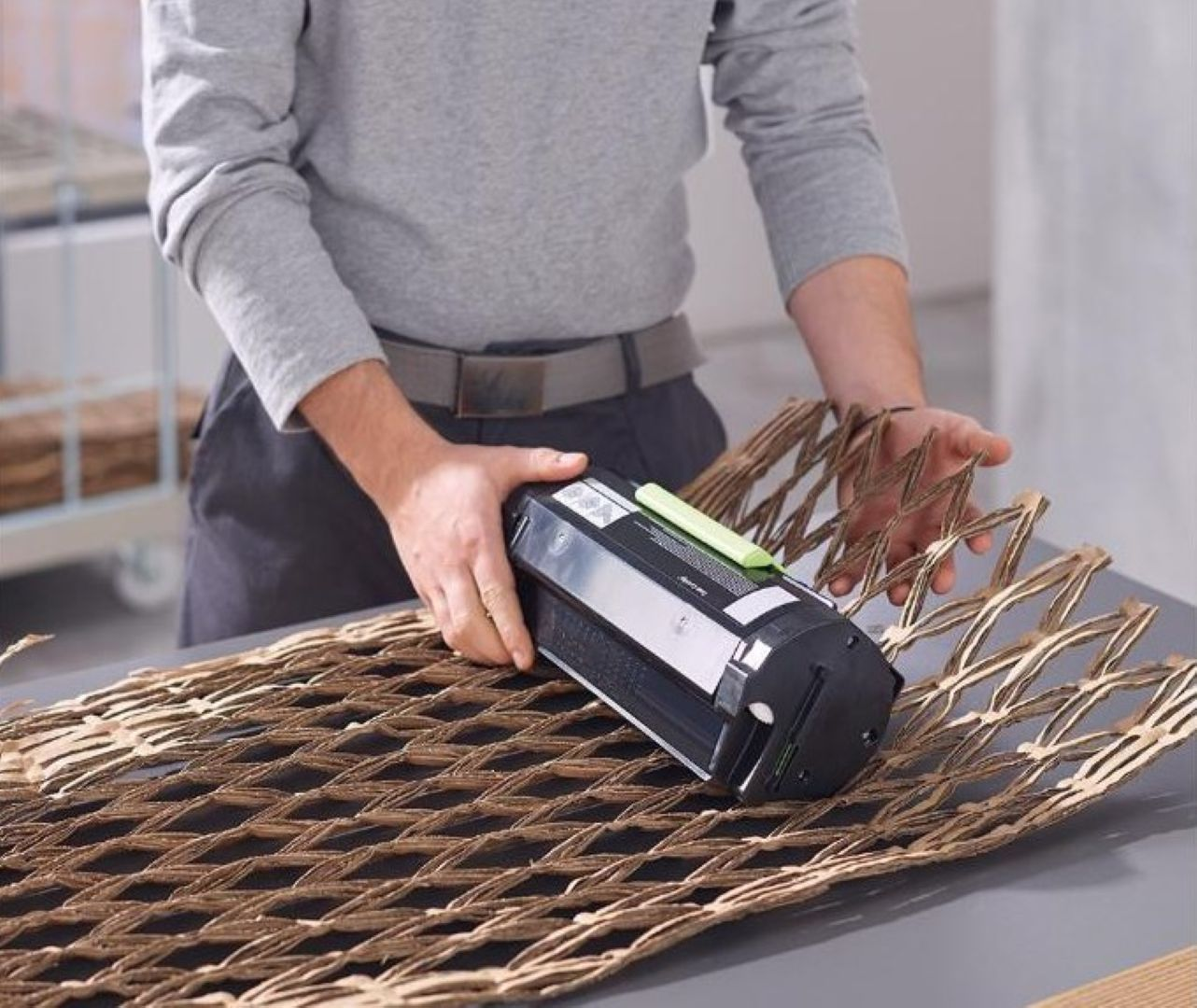 Bir kişi yazıcı kartuşunu kahverengi petek kağıdına paketliyor.