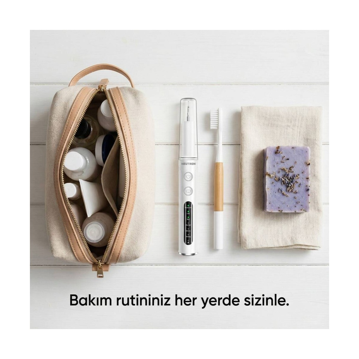 Taşınabilir bakım çantası, diş fırçası, sabun ve havlu ahşap zeminde.