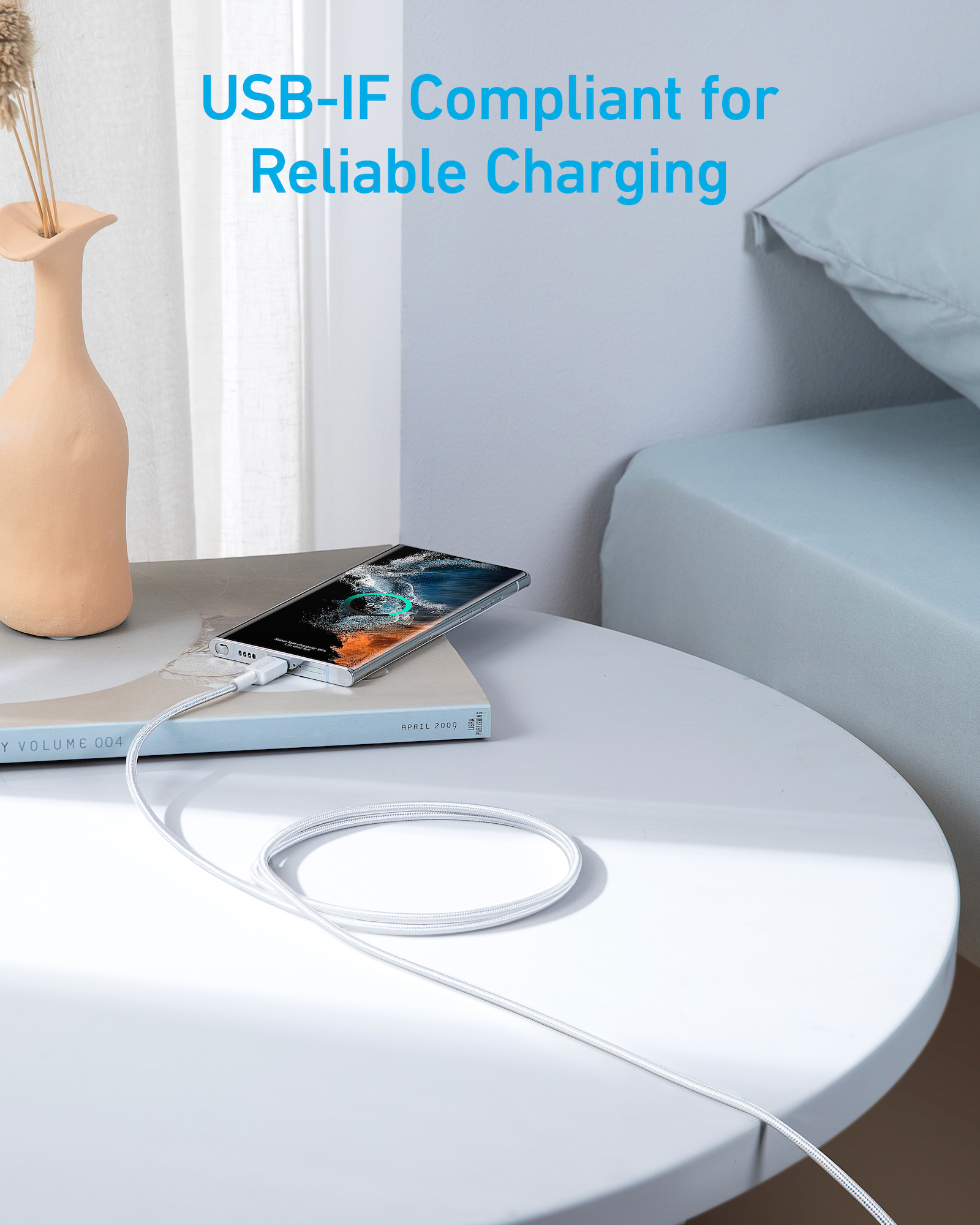 Ein Smartphone wird über ein weißes USB-Kabel an ein Buch angeschlossen.