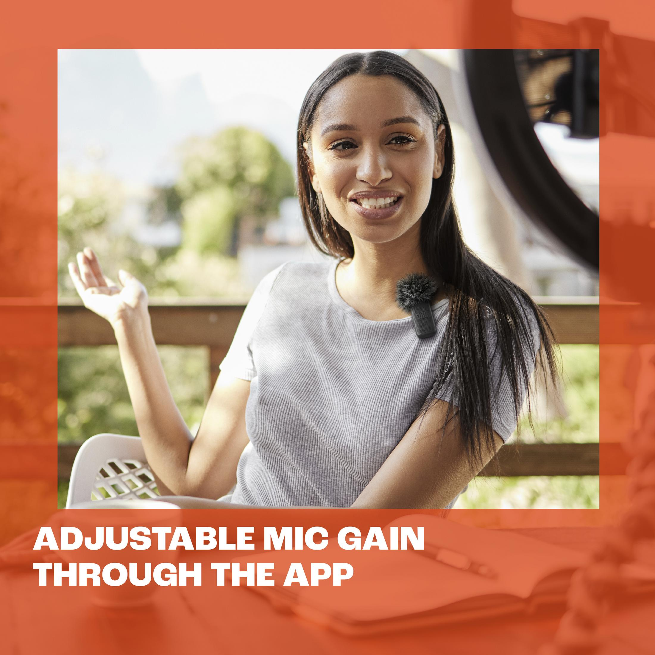 Kobieta siedzi na krześle, uśmiecha się i gestykuluje. Mikrofon jest przypięty do kołnierza.