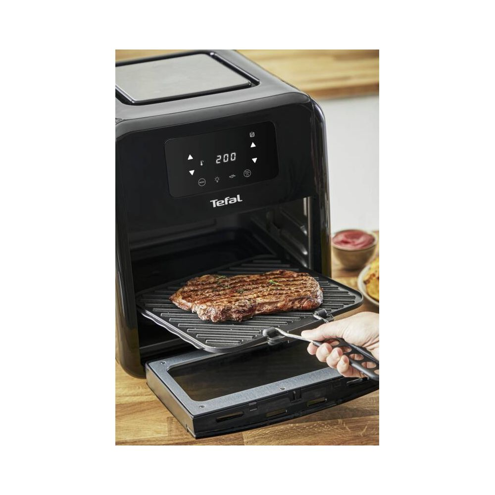 Grillowany stek jest wyjmowany z czarnego piekarnika Tefal z cyfrowym wyświetlaczem.