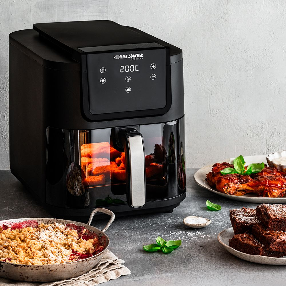 Czarna frytkownica beztłuszczowa z kruszonką owocową, kurczakiem i brownie na szarej powierzchni.