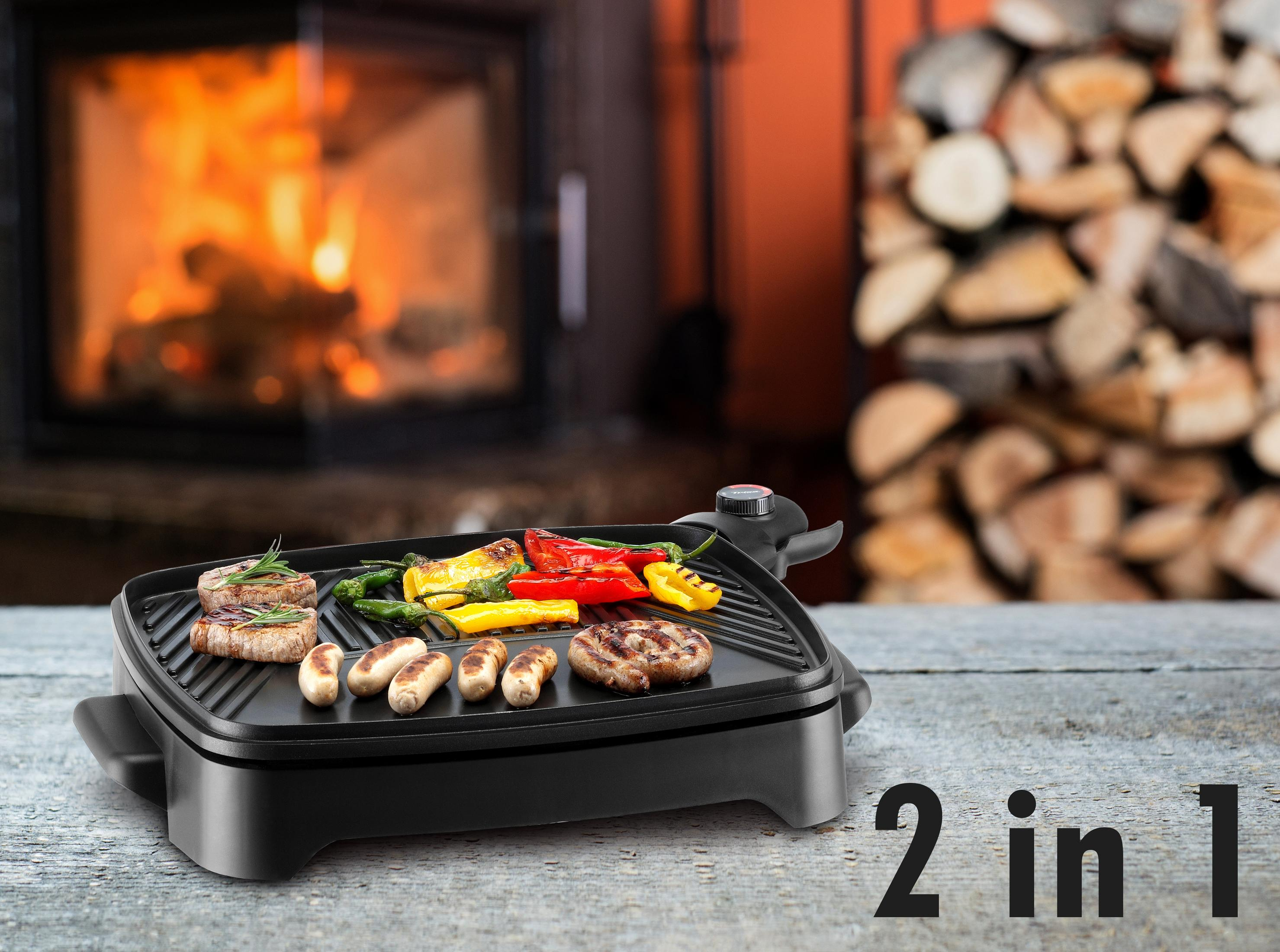 Elektrischer Grill mit Fleisch, Würstchen und Gemüse vor einem Kamin.