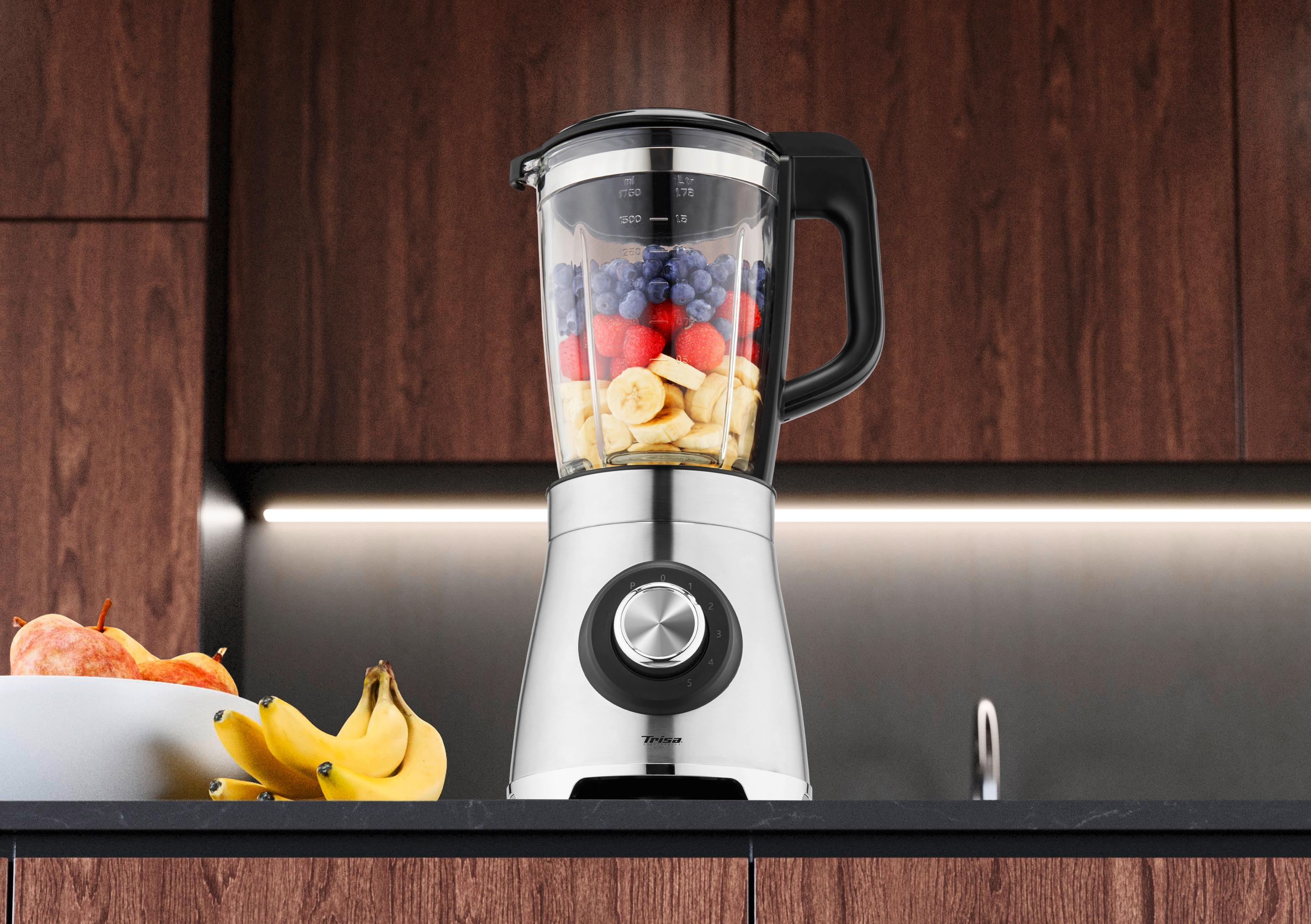 Ein silberner Mixer mit Beeren, Bananen und Erdbeeren gefüllt.