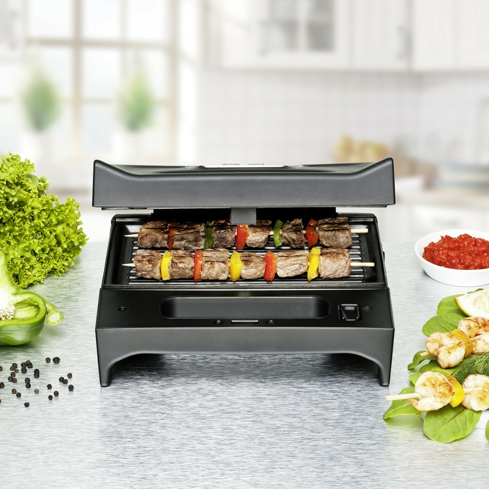 Parrilla con brochetas de carne y verduras, camarones y ensalada en una mesa.