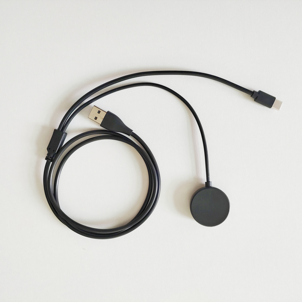 Ein schwarzes USB-C-Ladekabel mit rundem magnetischem Ladepad.