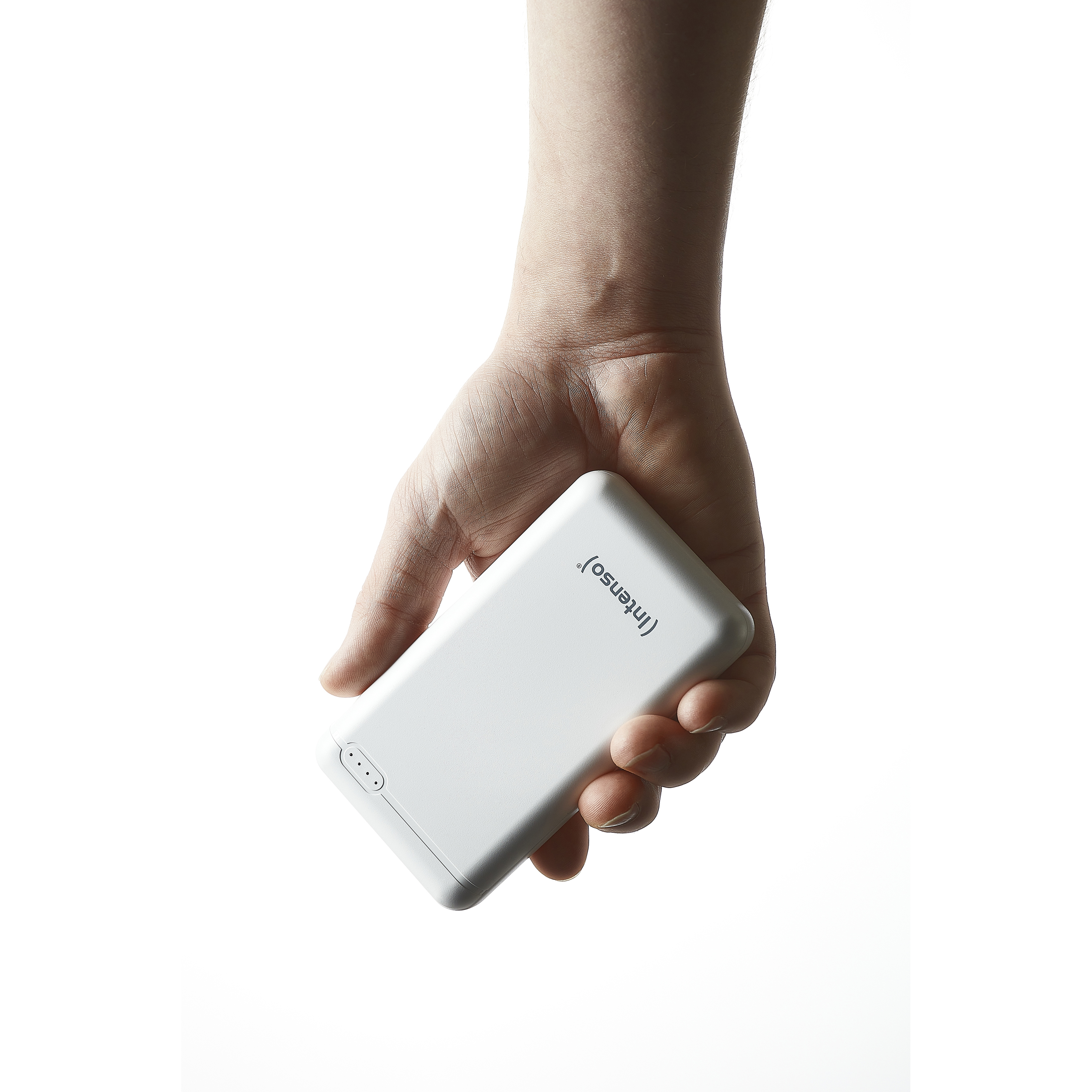 Una mano sostiene un dispositivo de batería externa blanco con el logo "Intenso".