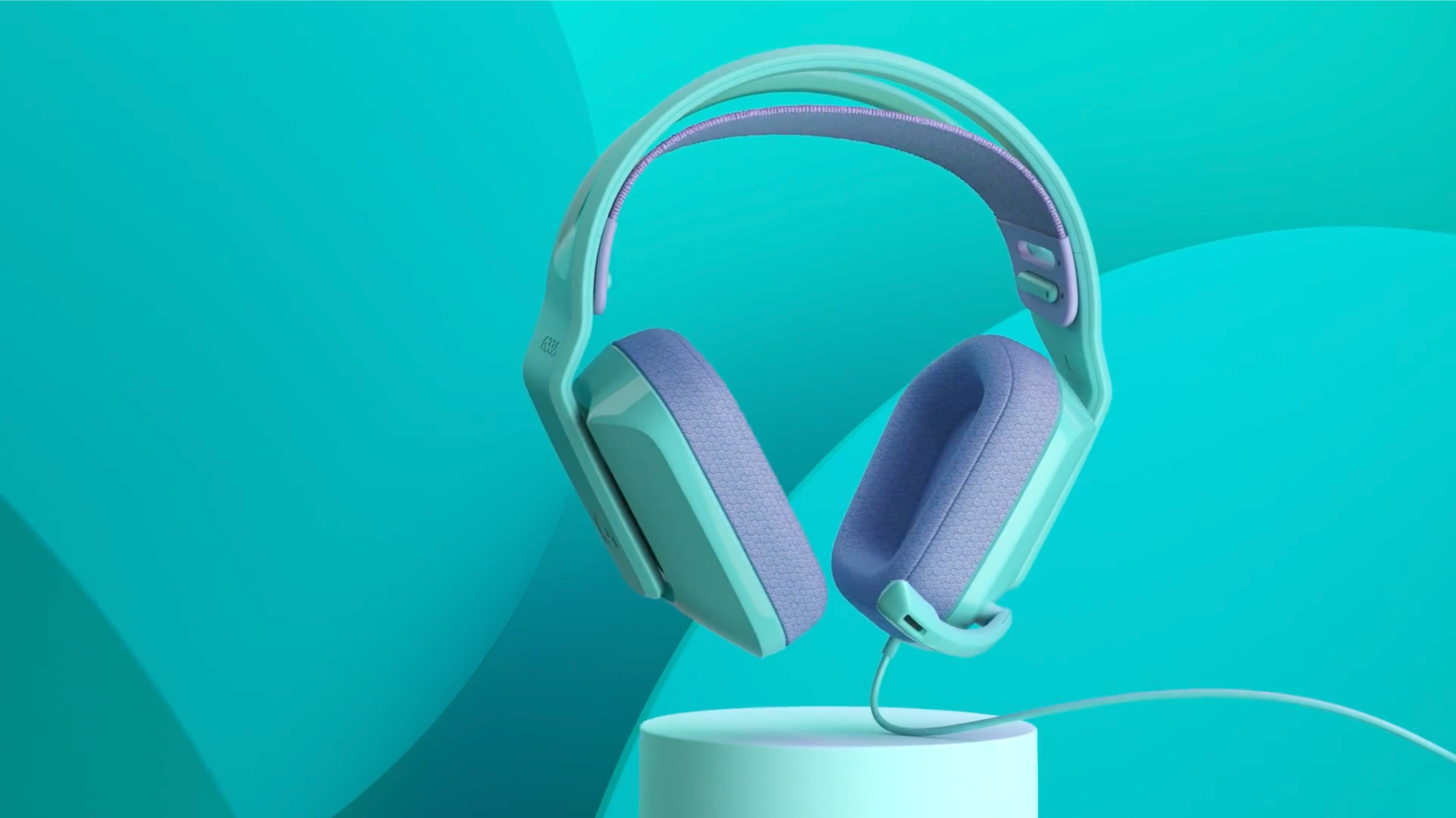 Jasnoniebieskie i fioletowe słuchawki przewodowe na postumencie na tle turkusowym.
