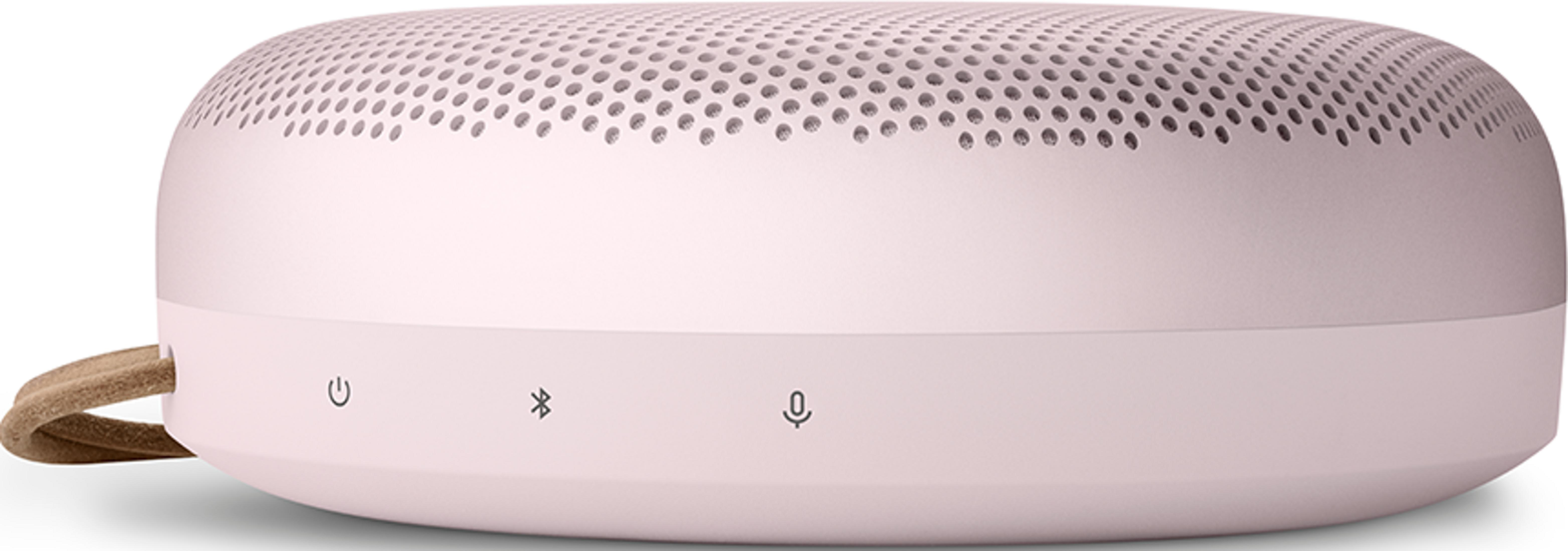 Różowy głośnik z perforowaną górą i pętelką po lewej stronie.