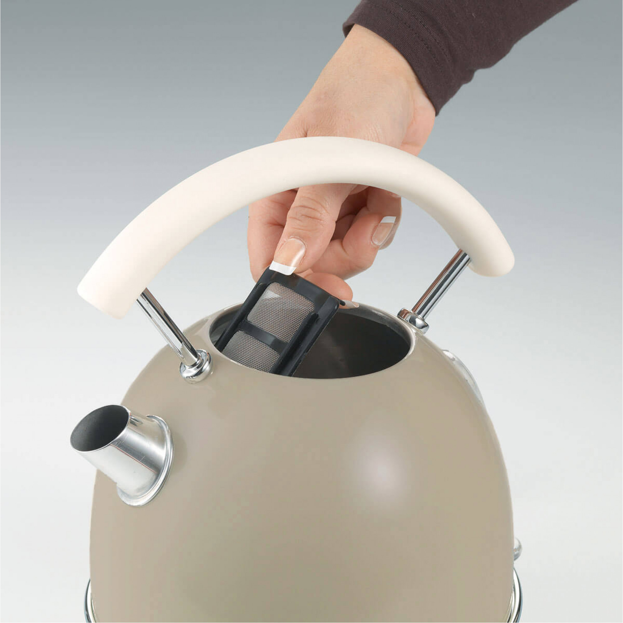 Eine Hand setzt einen schwarzen Wasserfilter in einen beigefarbenen Wasserkocher ein.