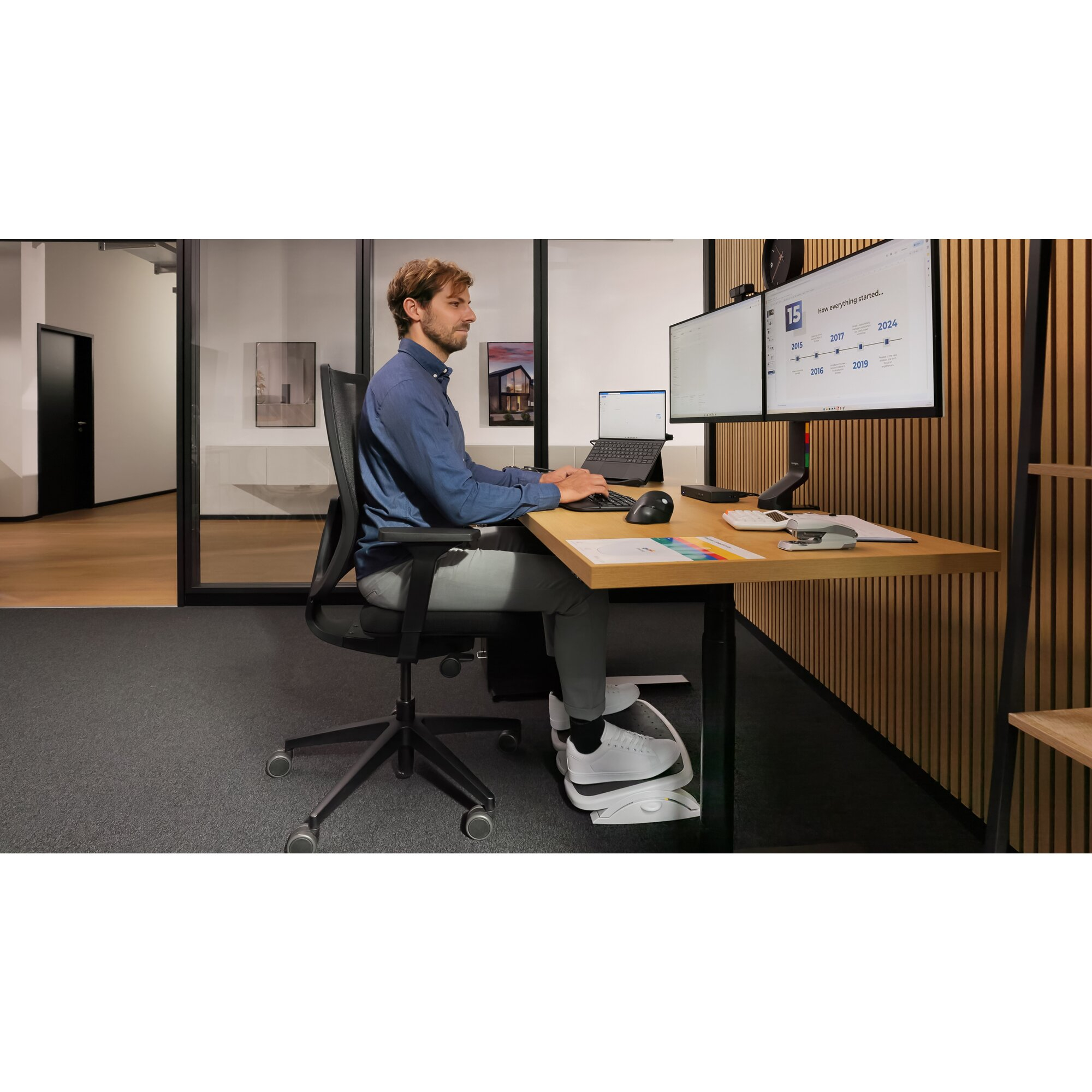 Ein Mann sitzt an einem Schreibtisch mit zwei Monitoren und tippt auf einer Tastatur.