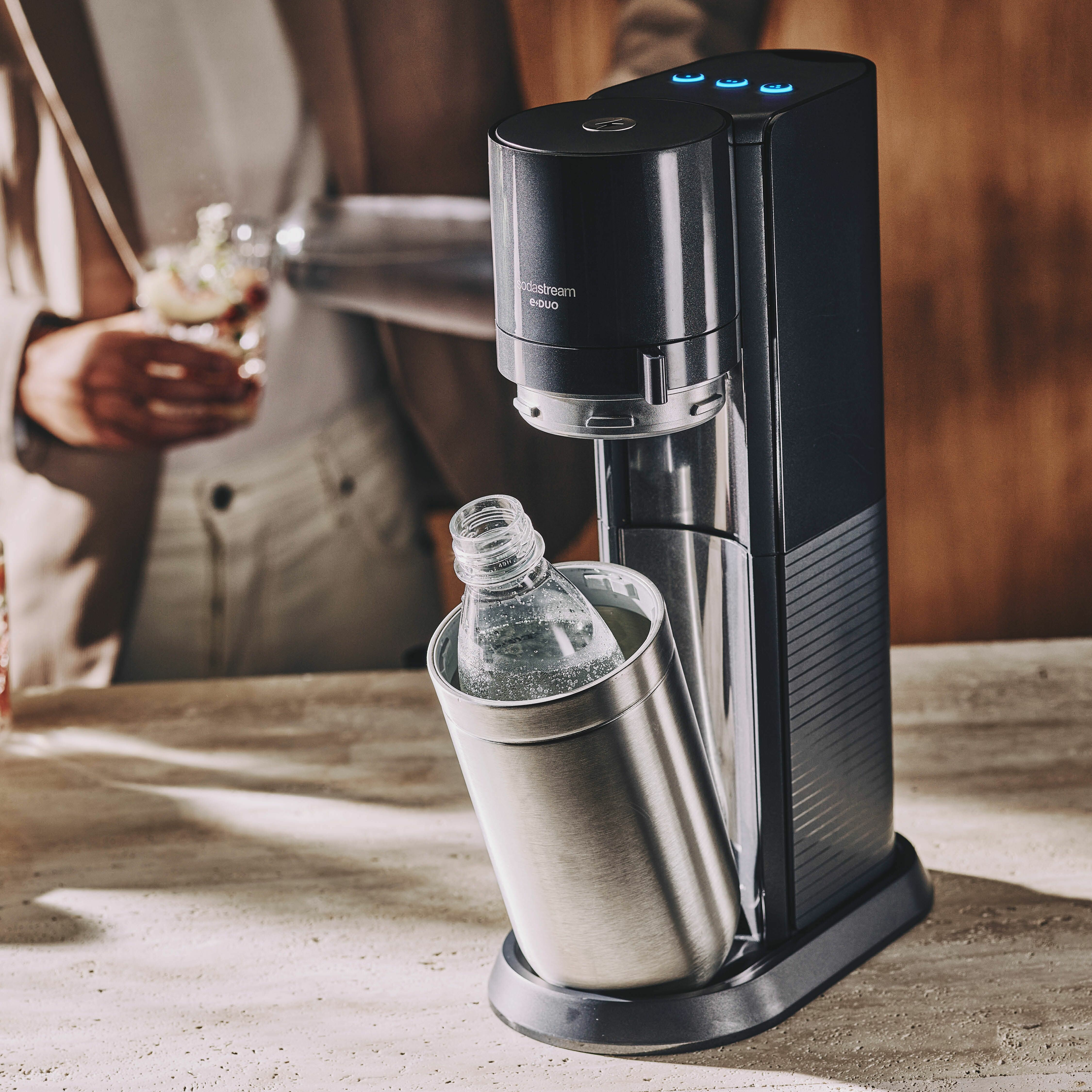 Ein schwarzer Sodastream-Wassersprudler mit einer Glasflasche daneben.
