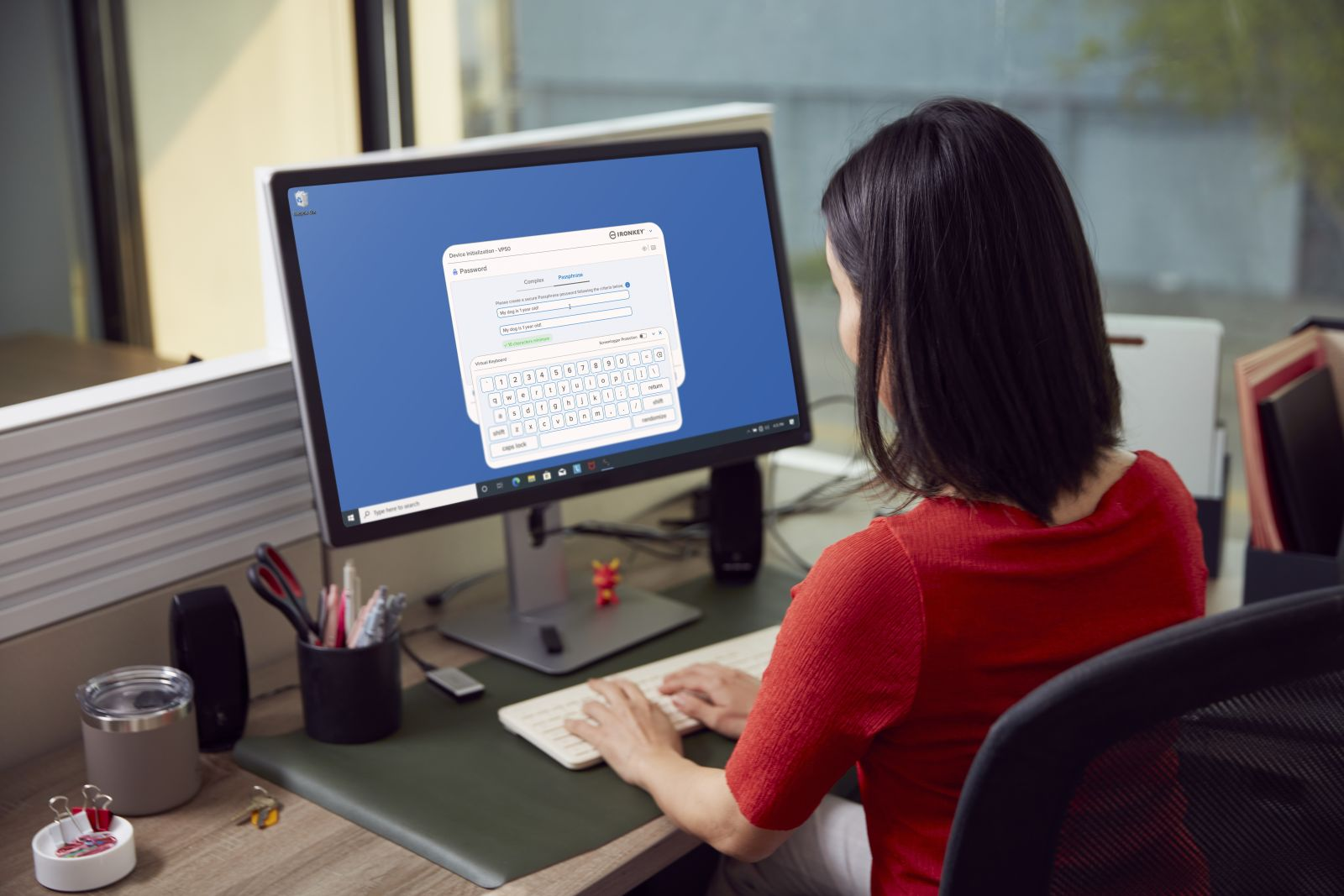 Kobieta w czerwonym topie pisze na klawiaturze przed ekranem komputera z wirtualną klawiaturą.