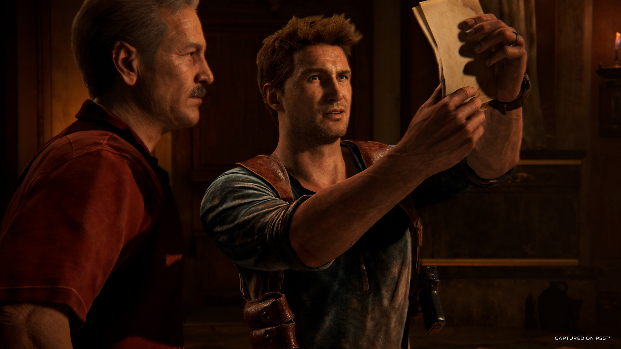 Two men in a dark room, one examining an old document.