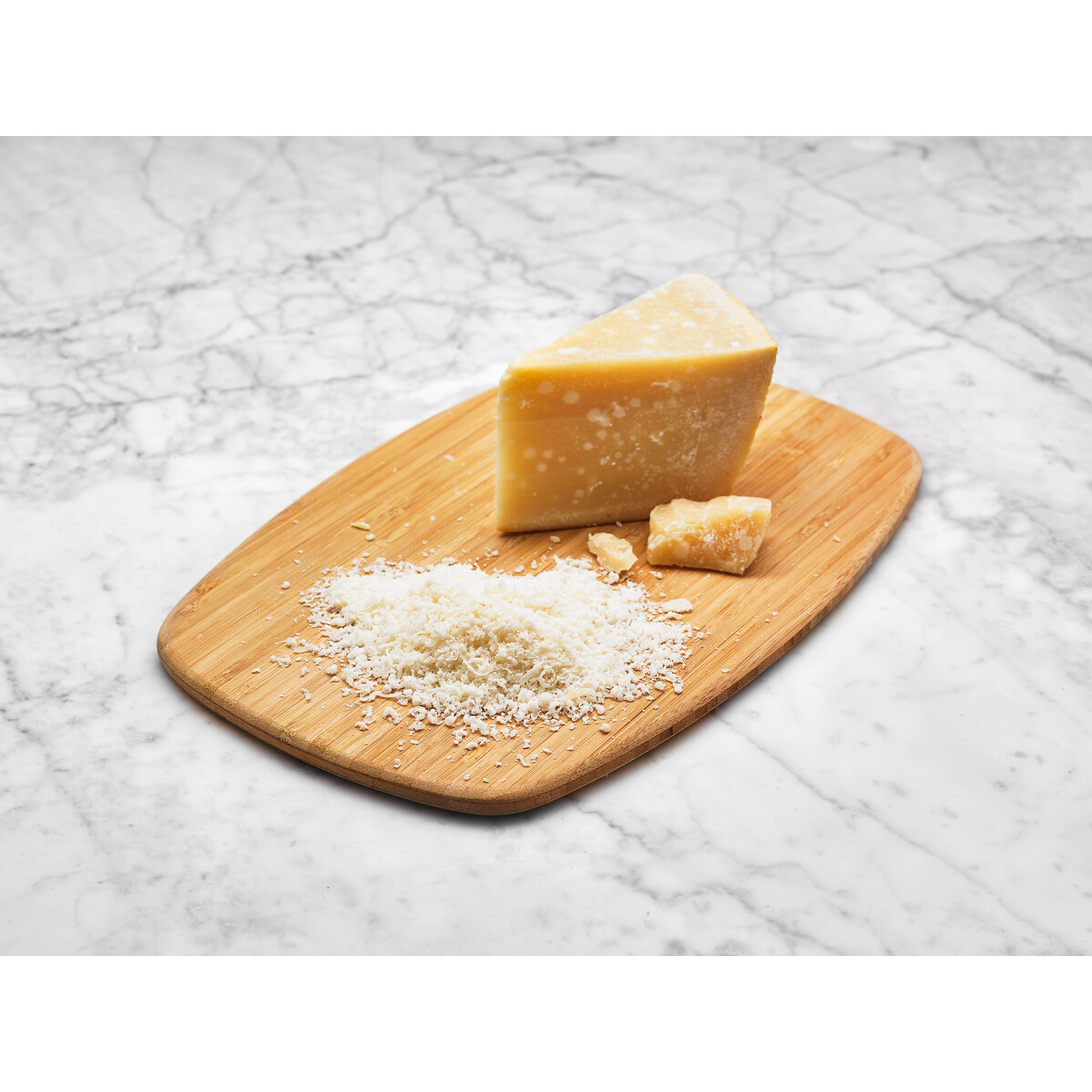 Ein Stück Parmesan und geriebener Käse auf einem Holzbrett.