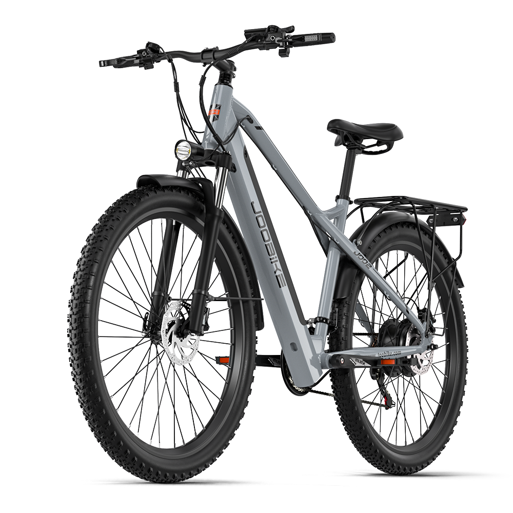 Ein graues E-Bike mit breiten Reifen, Federgabel, Gepäckträger und Scheinwerfer.