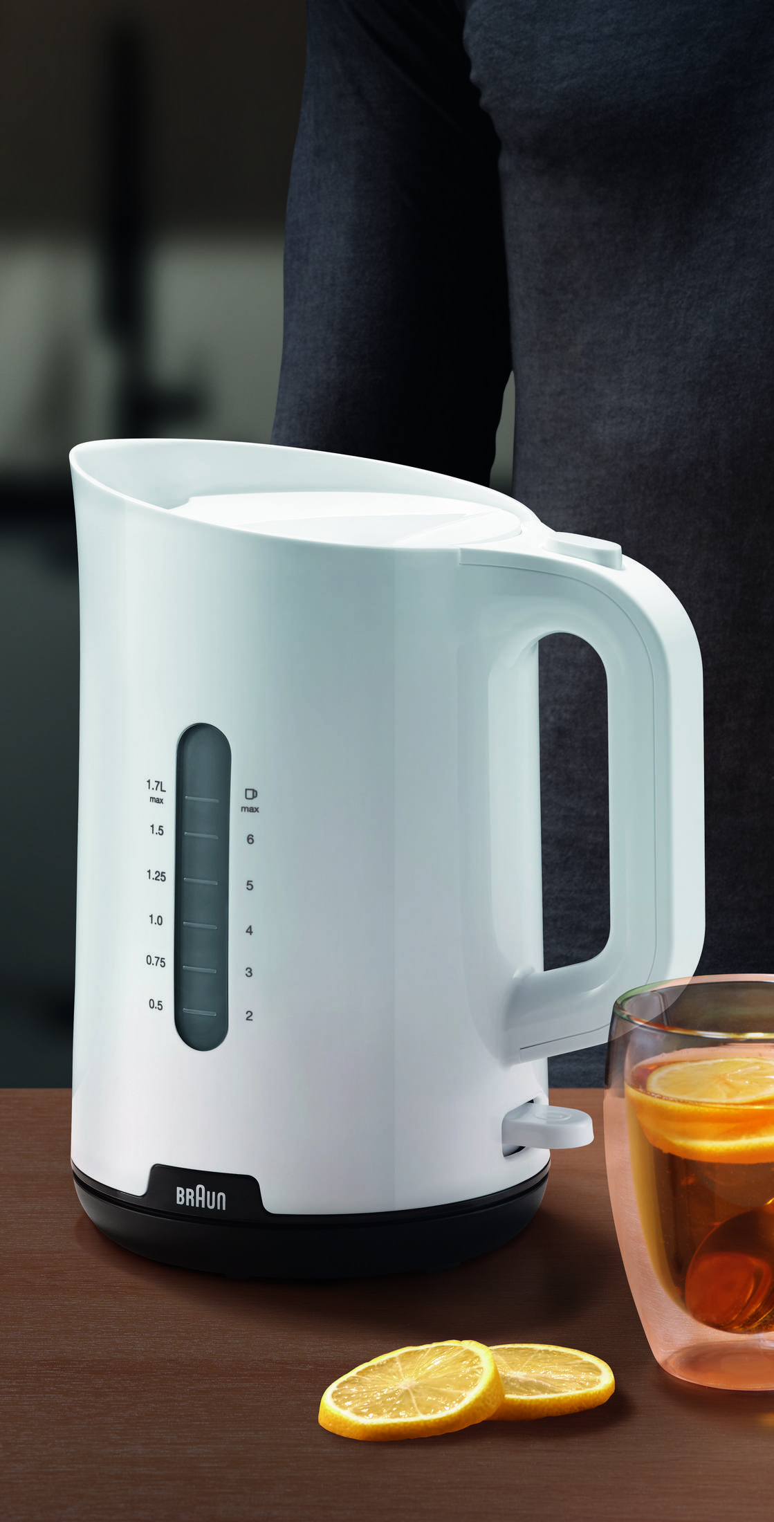 Eine weiße Braun-Kaffeemaschine mit Wasserstandsanzeige neben einem Glas Tee.