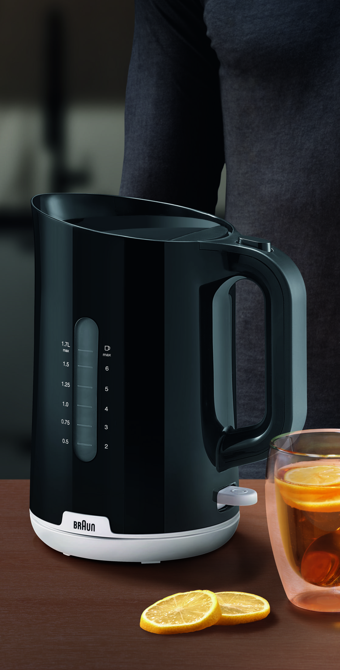 Czajnik elektryczny Braun w kolorze czarnym ze szklanką herbaty i plasterkami cytryny.