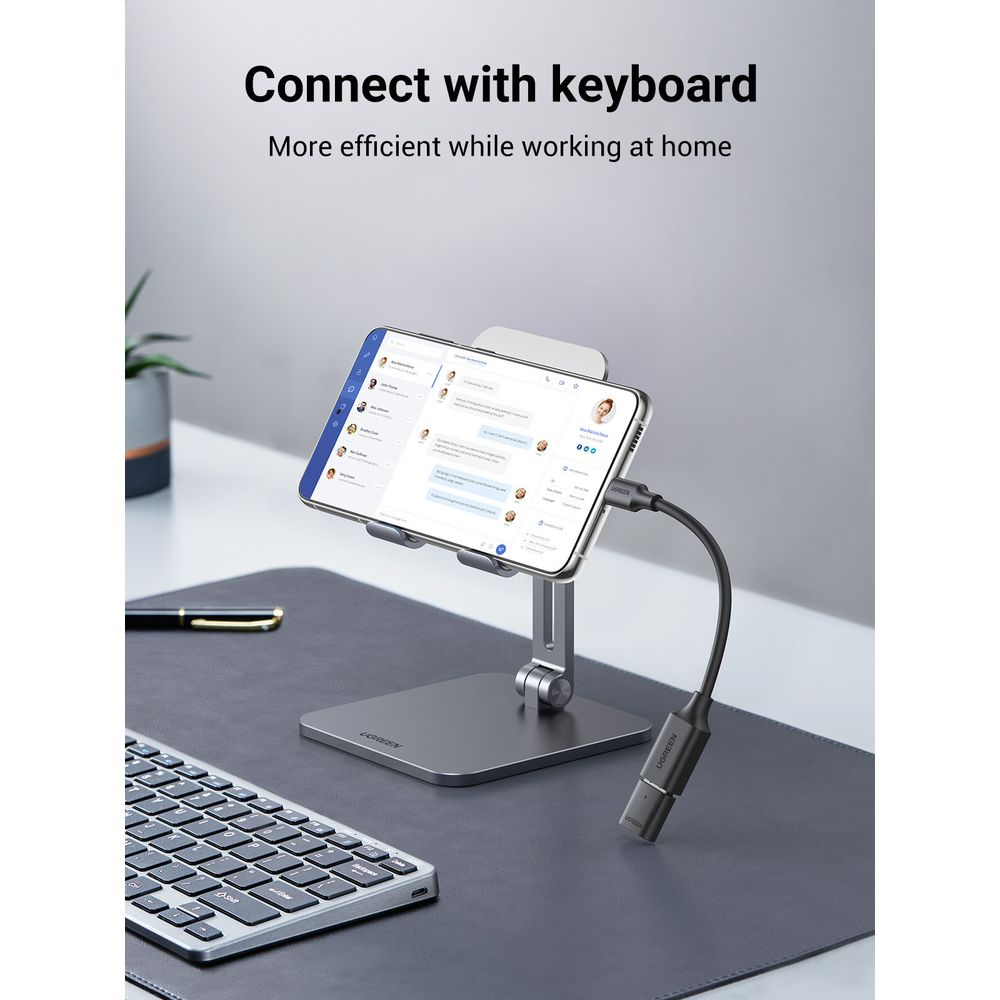 Smartfon na stojaku wyświetla aplikację czatu. W pobliżu klawiatura i długopis.