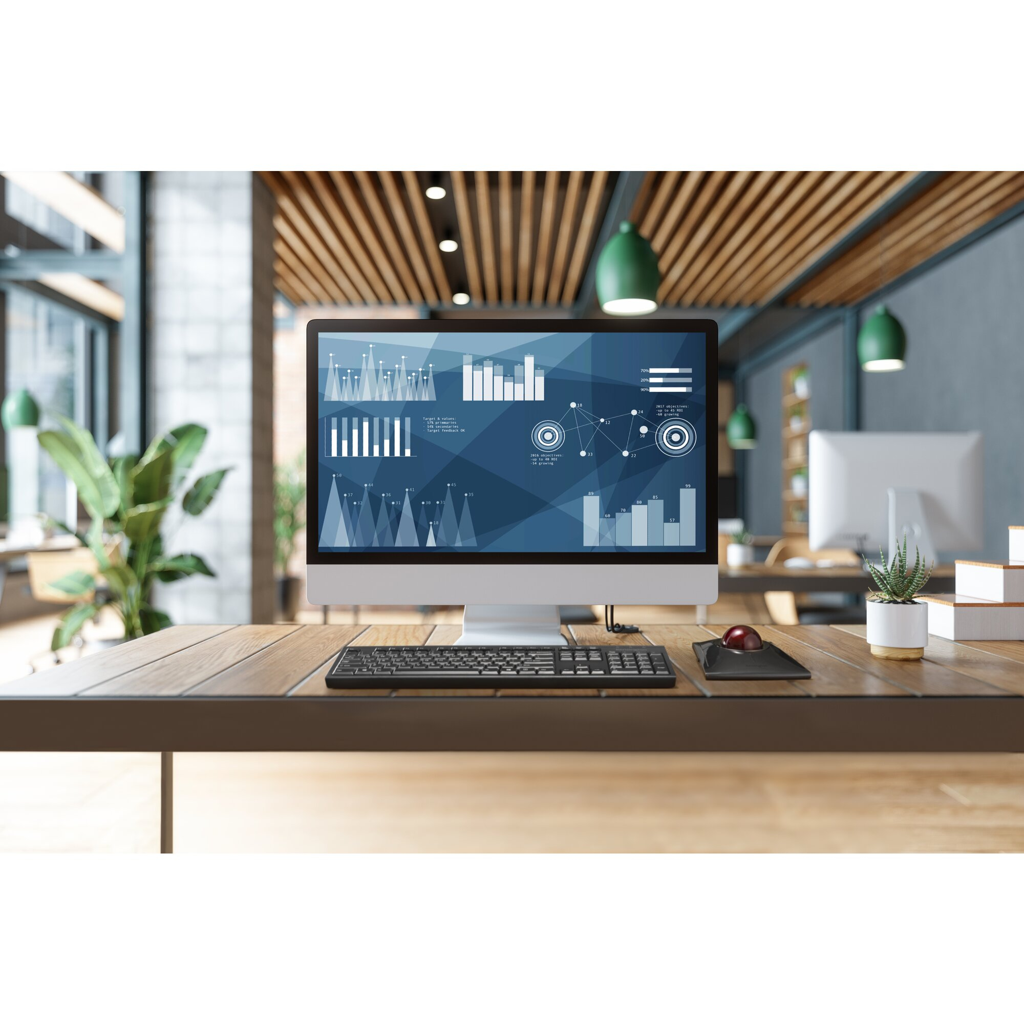 Biurko z komputerem wyświetlającym wykresy. Nowoczesna przestrzeń biurowa w tle.
