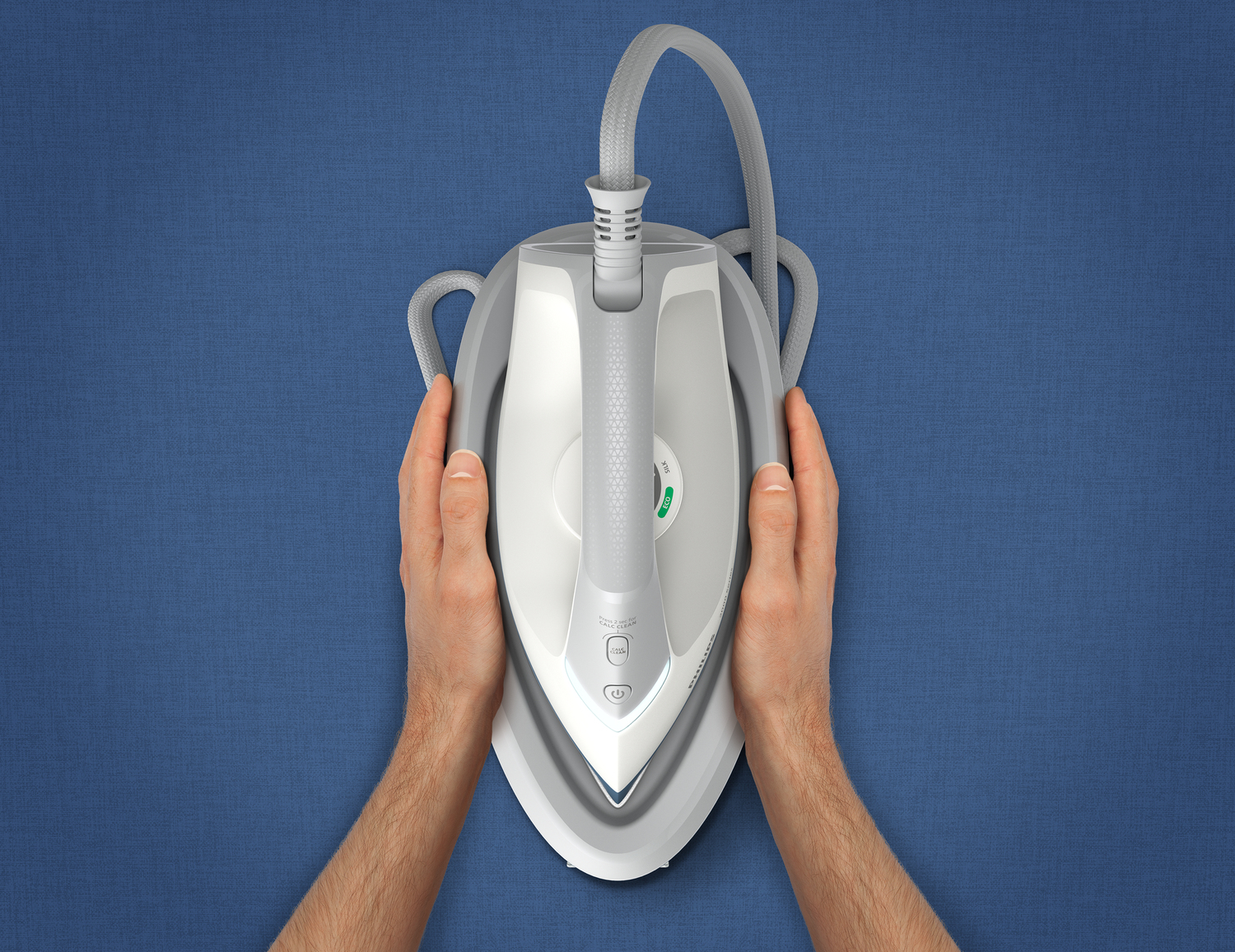 Dłonie trzymające żelazko parowe na niebieskiej tkaninie.