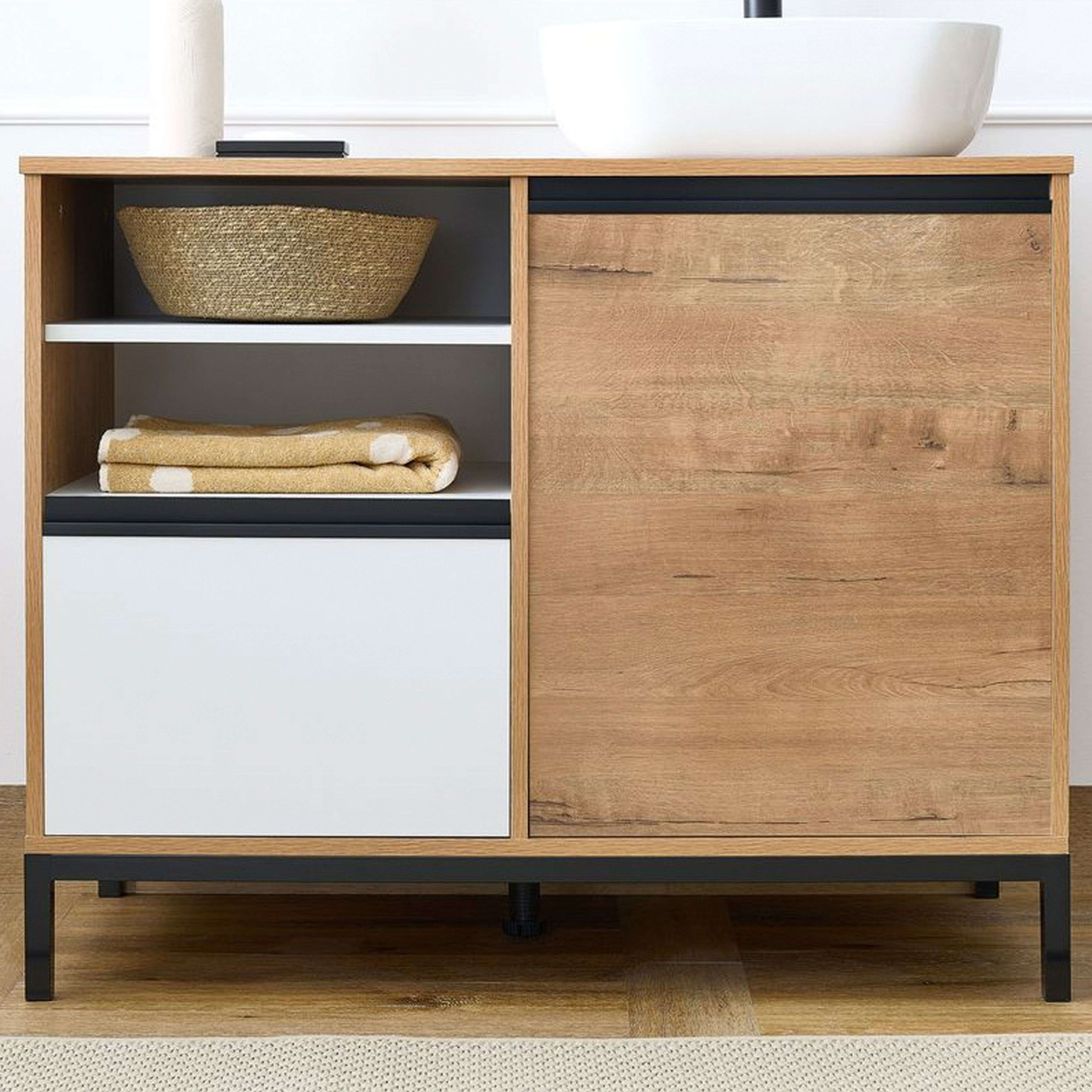 Un mueble de tocador de madera con cesta, toallas y compartimento blanco.