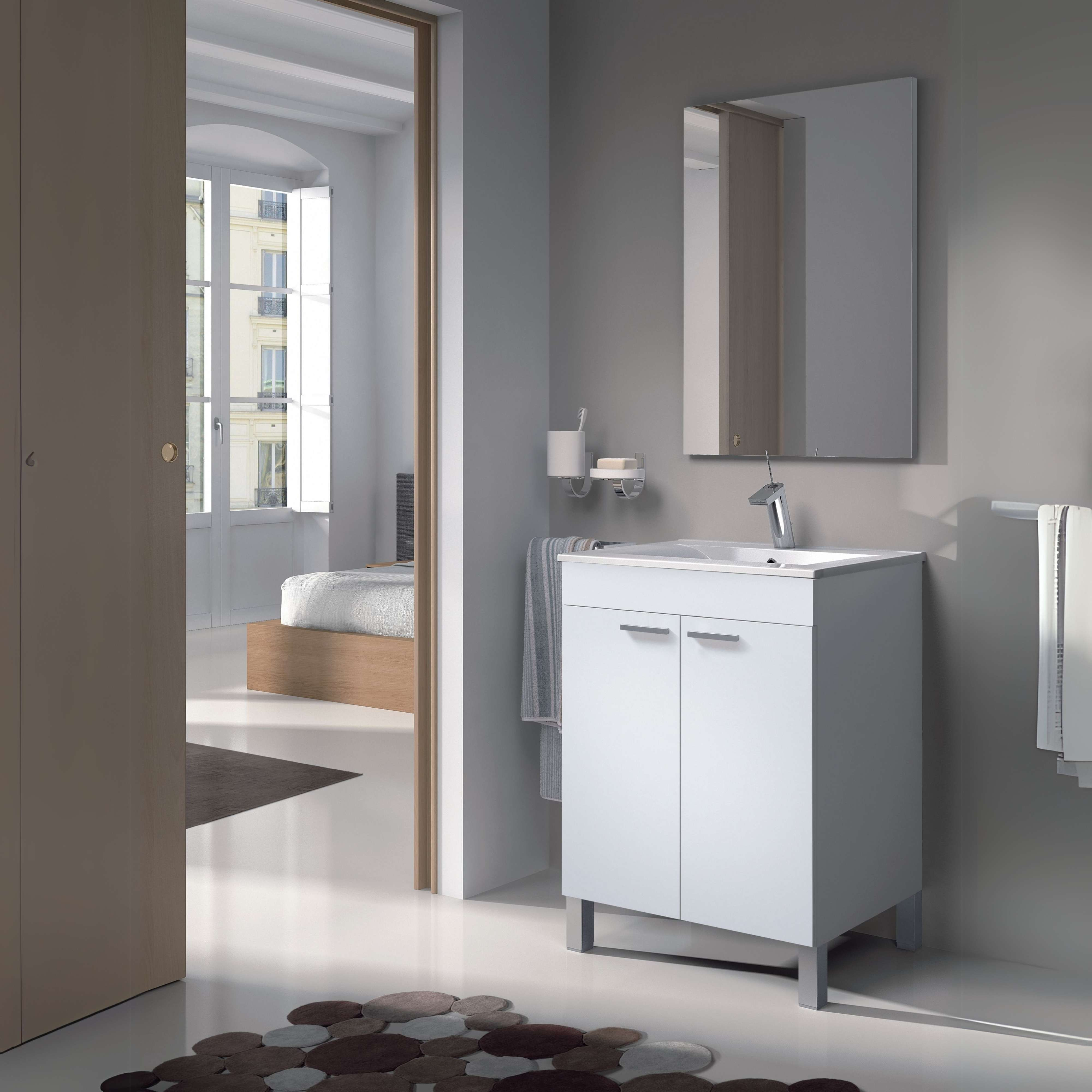 Baño moderno con tocador blanco, espejo y vista a un dormitorio.