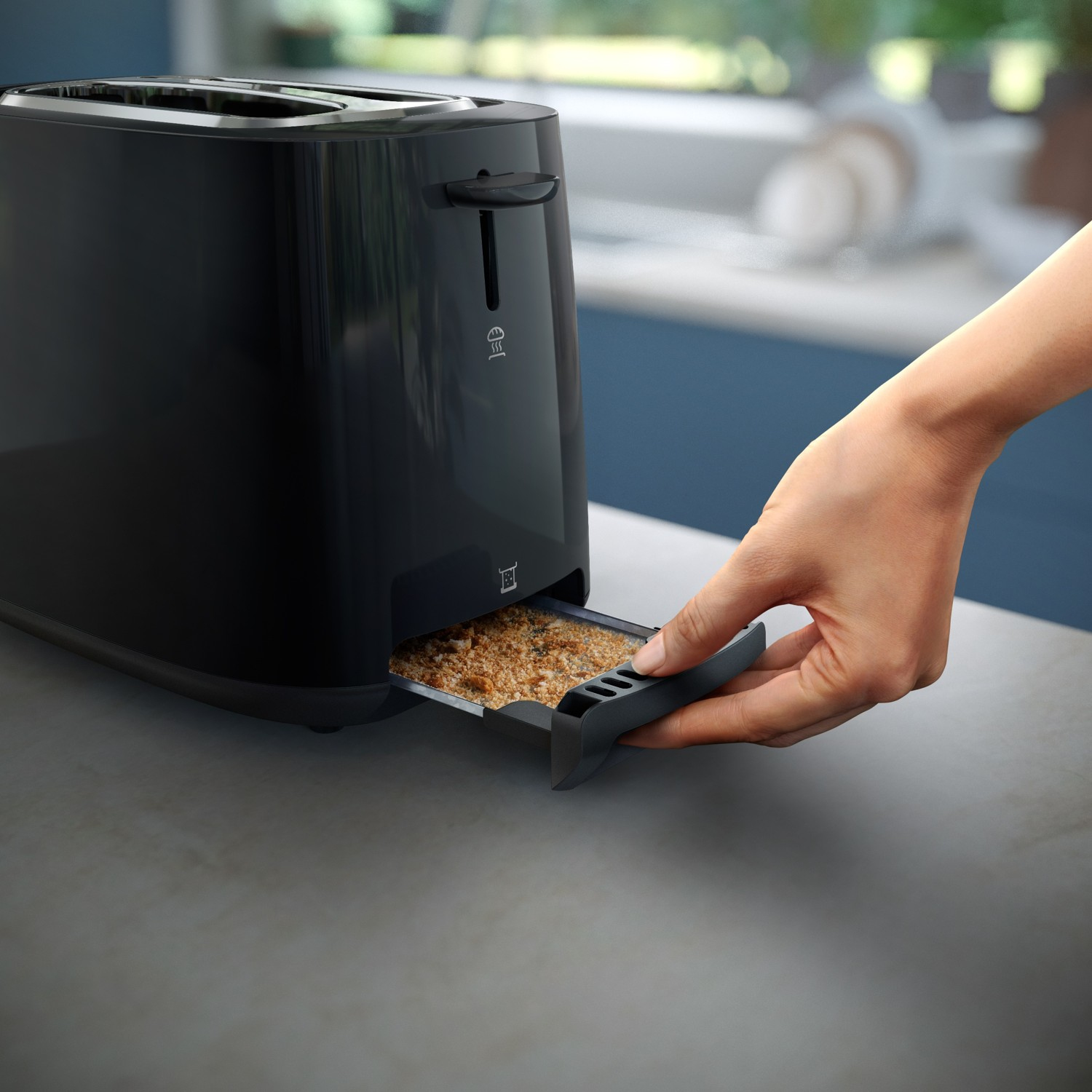 Ręka wyciąga tackę na okruchy spod czarnego tostera.