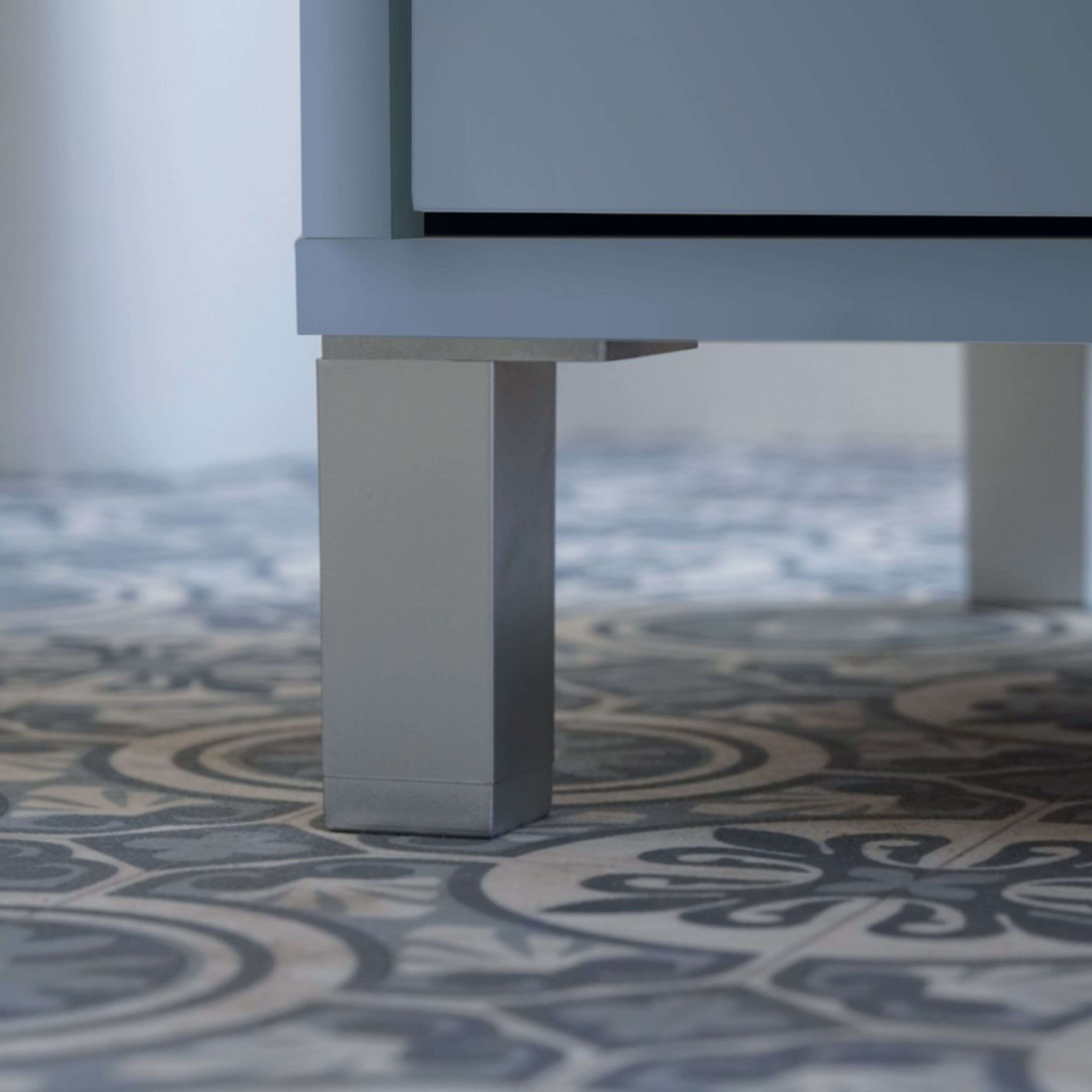 Una pata de mueble plateada se alza sobre un suelo estampado.